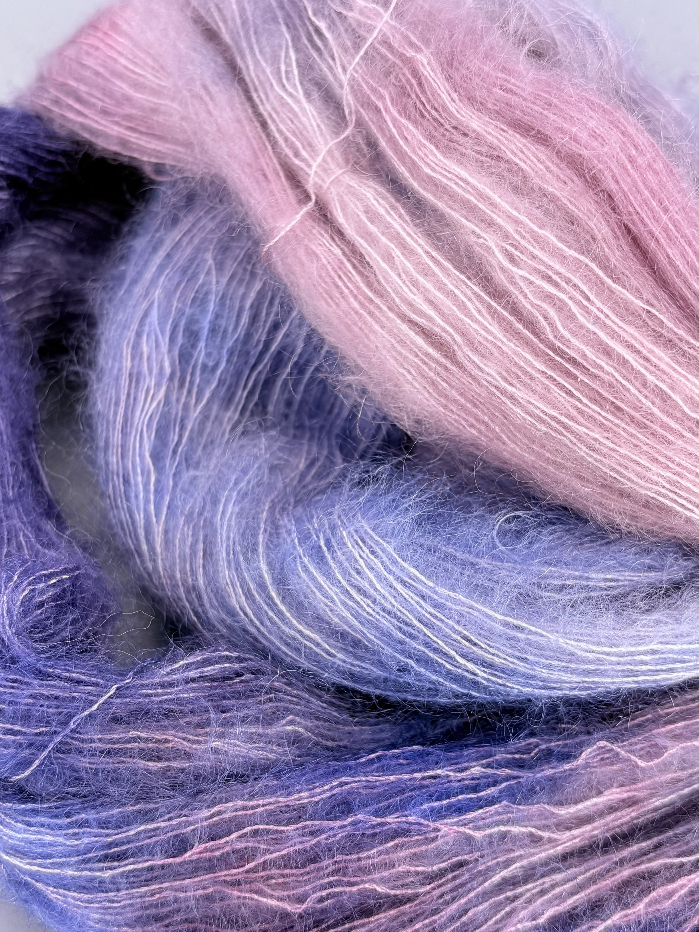 Close-up of pastel pink and purple yarn strands with a soft, fuzzy texture.