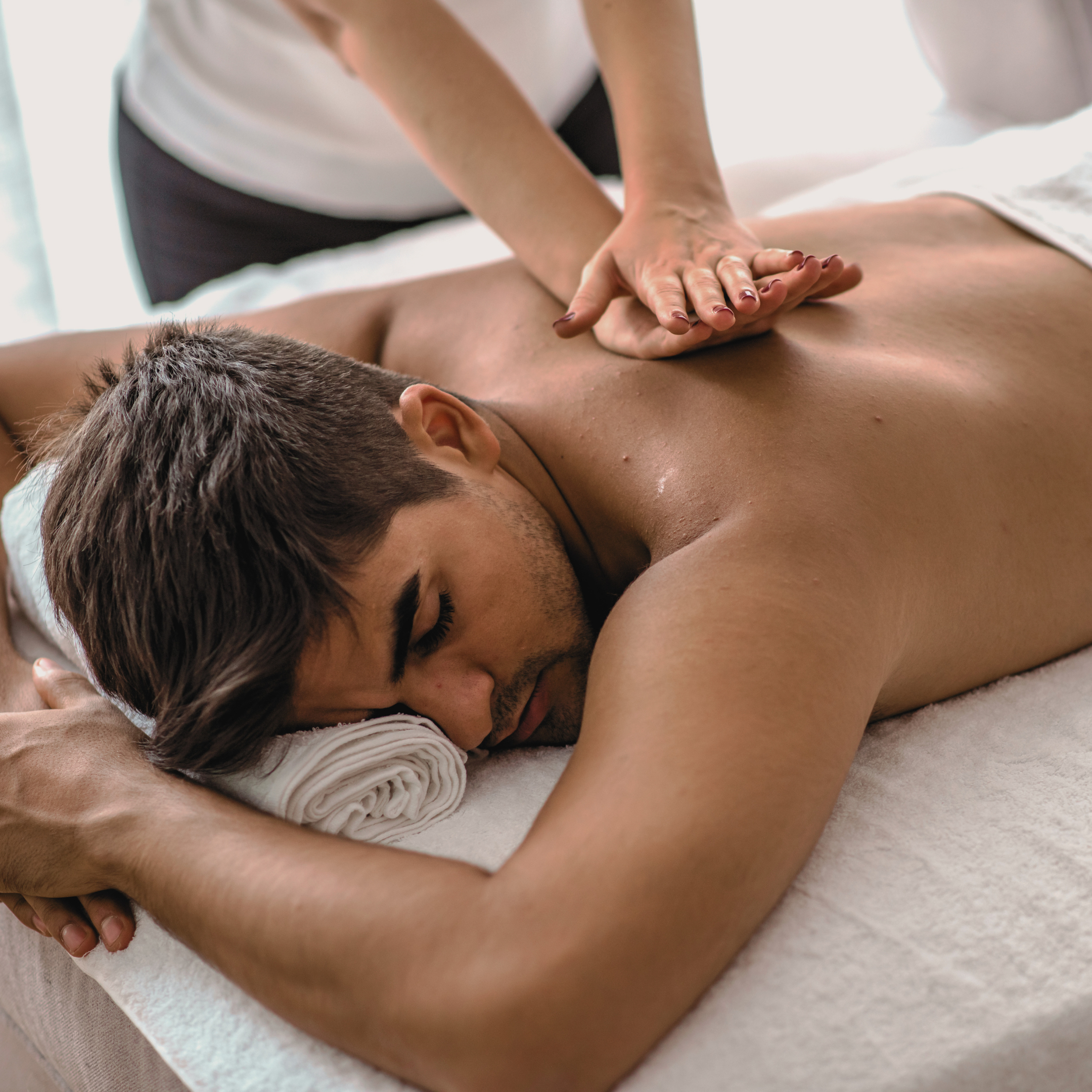 Person receiving a back massage from a therapist in a spa setting.