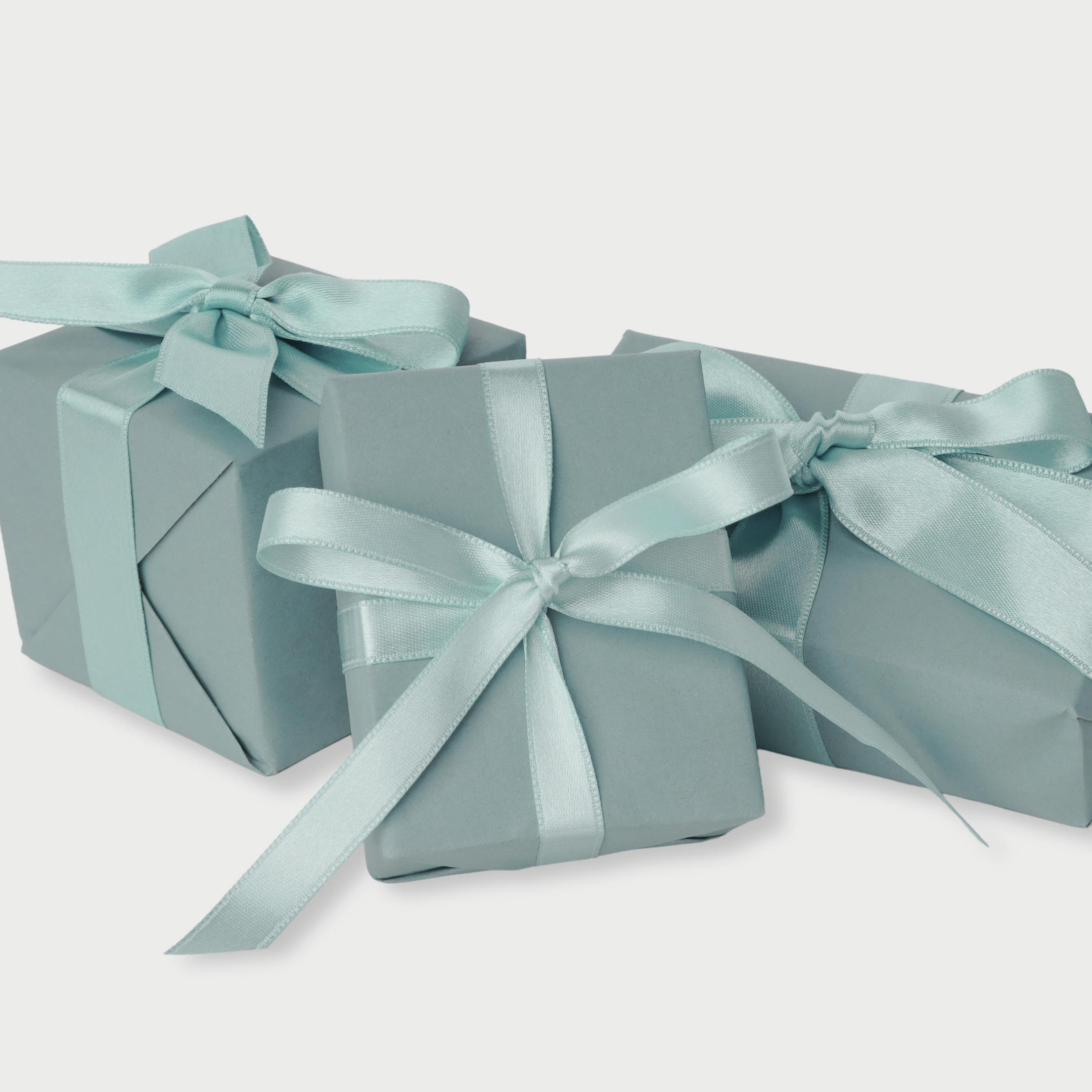 Three light blue gift boxes with satin ribbons and bows, arranged on a white background.