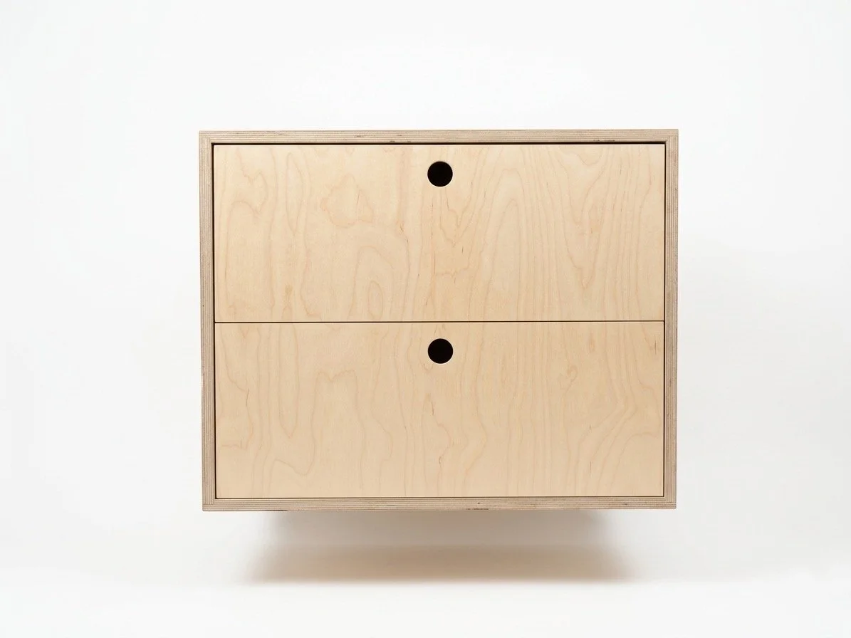 A minimalist birch plywood floating vanity cabinet with two drawers, each with a round handle.