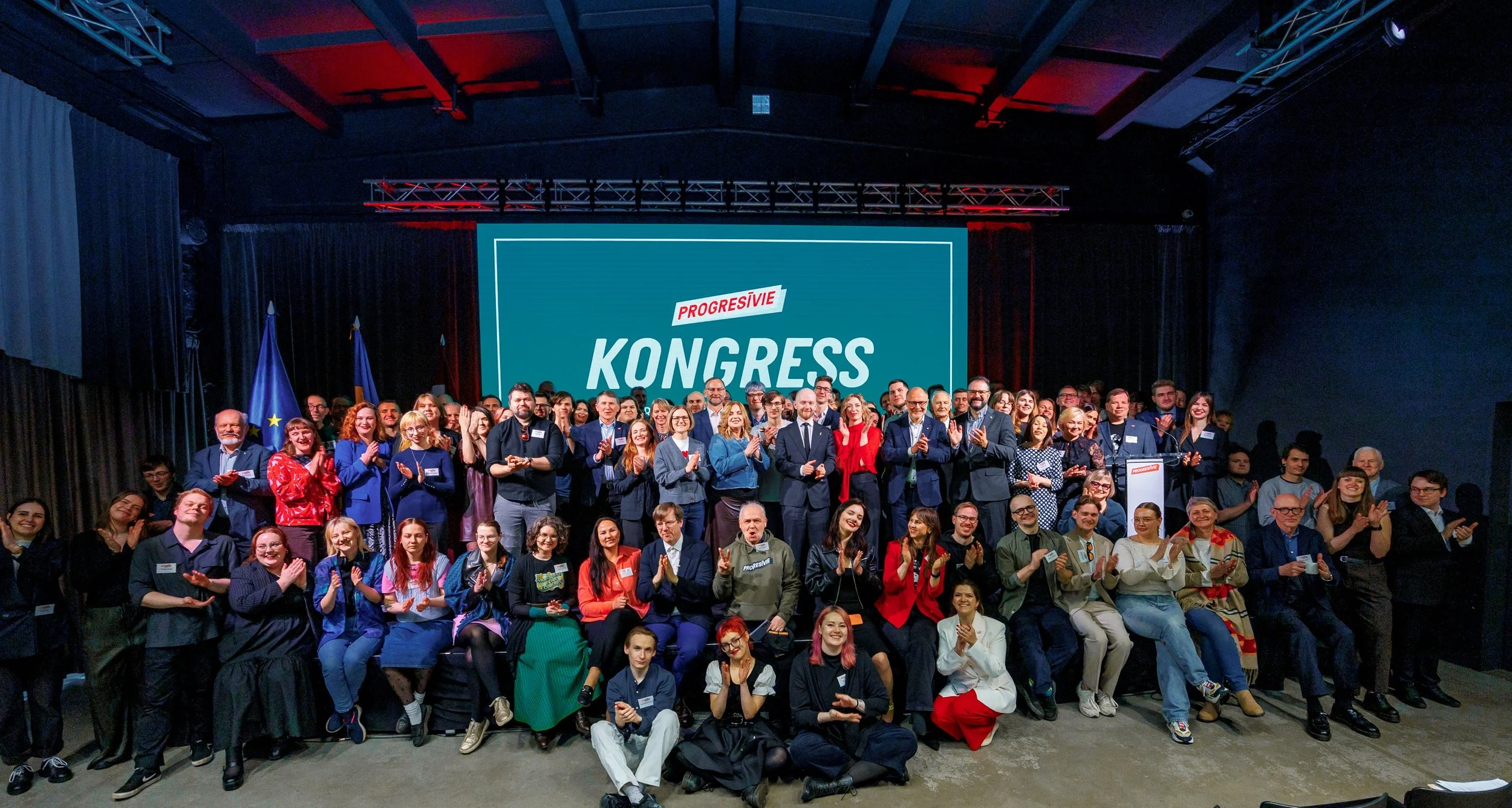 Progresīvie 2026. gada 25. aprīļa kongresa kopbilde. Redzams kongresa dalībnieki uz skatuves.