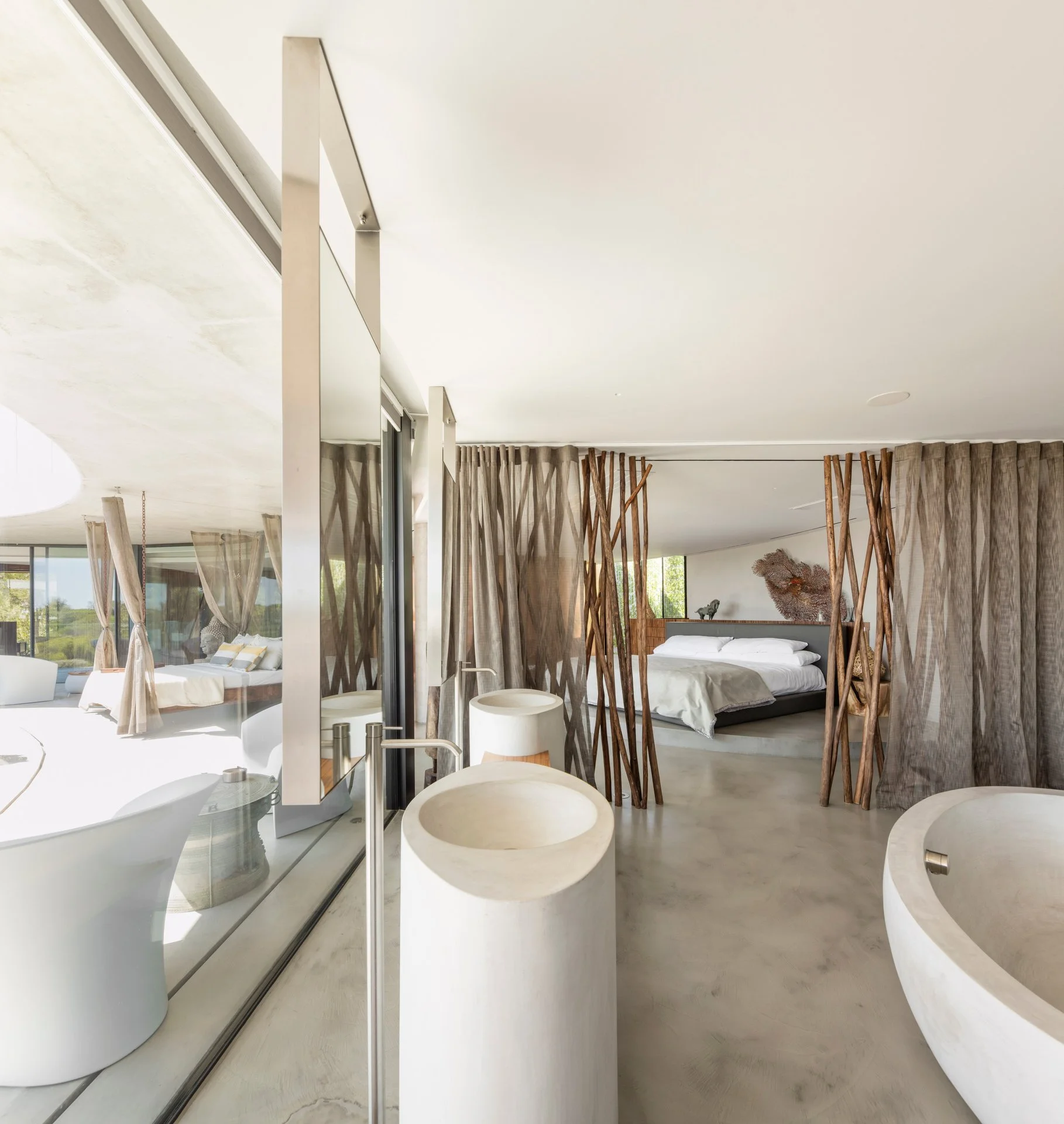 Master suite inspired by nature, with white and neutral tones and tree branches separating the bedroom from the bathroom