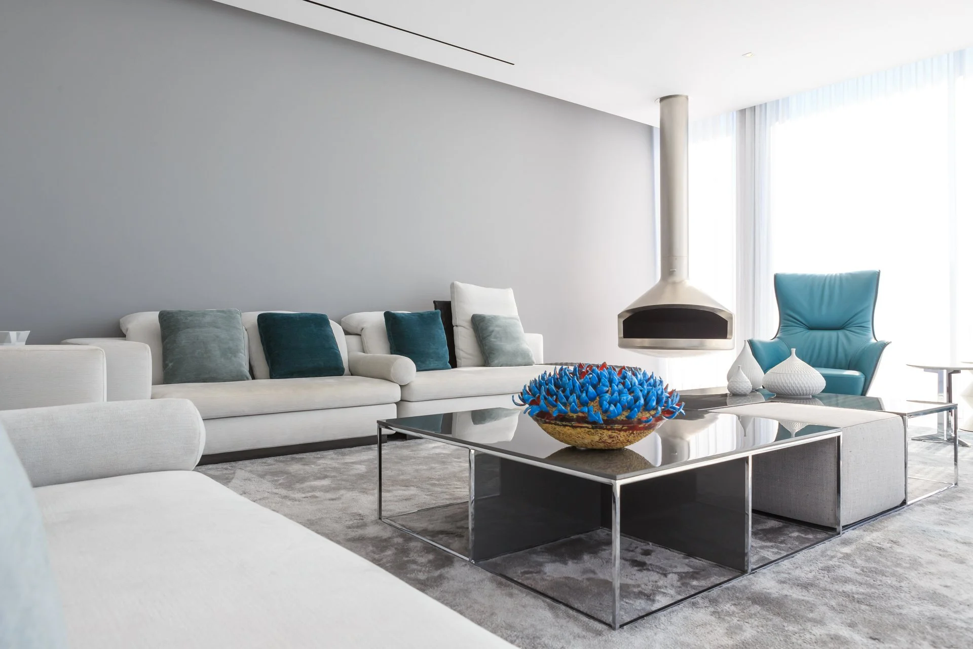 White and blue themed living room with modern furniture and a suspended fireplace