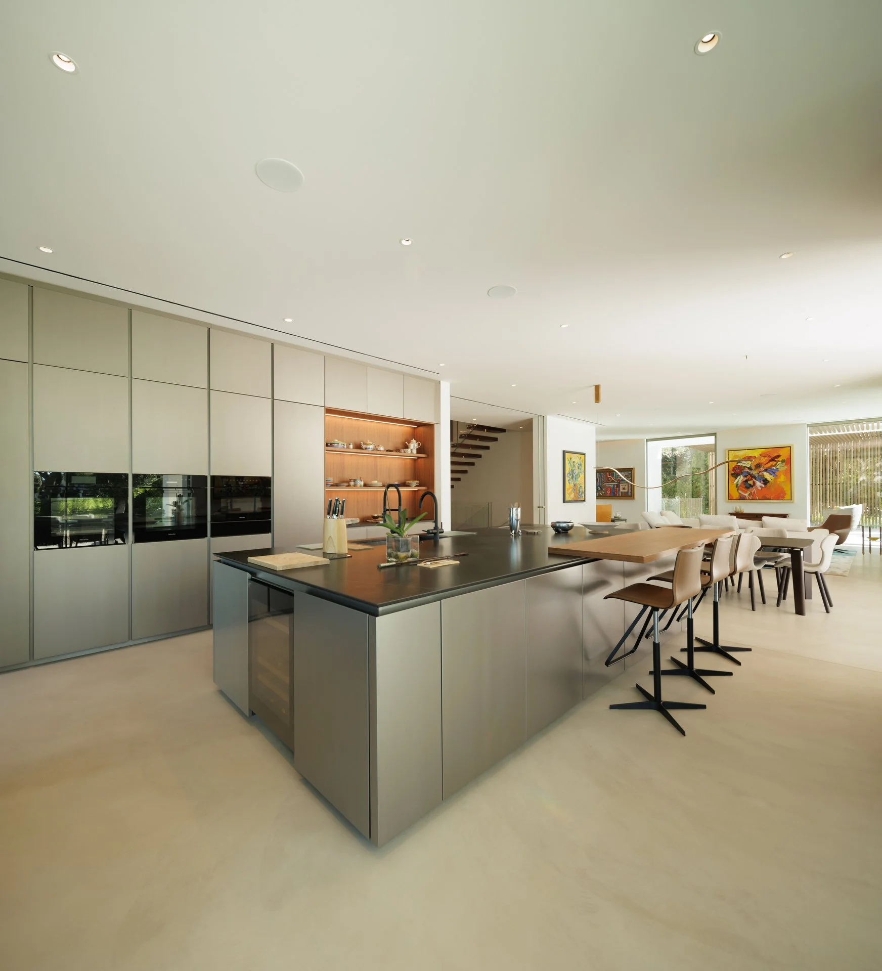 Large steel kitchen with an extensive island featuring a black counter top with a wooden dining extension
