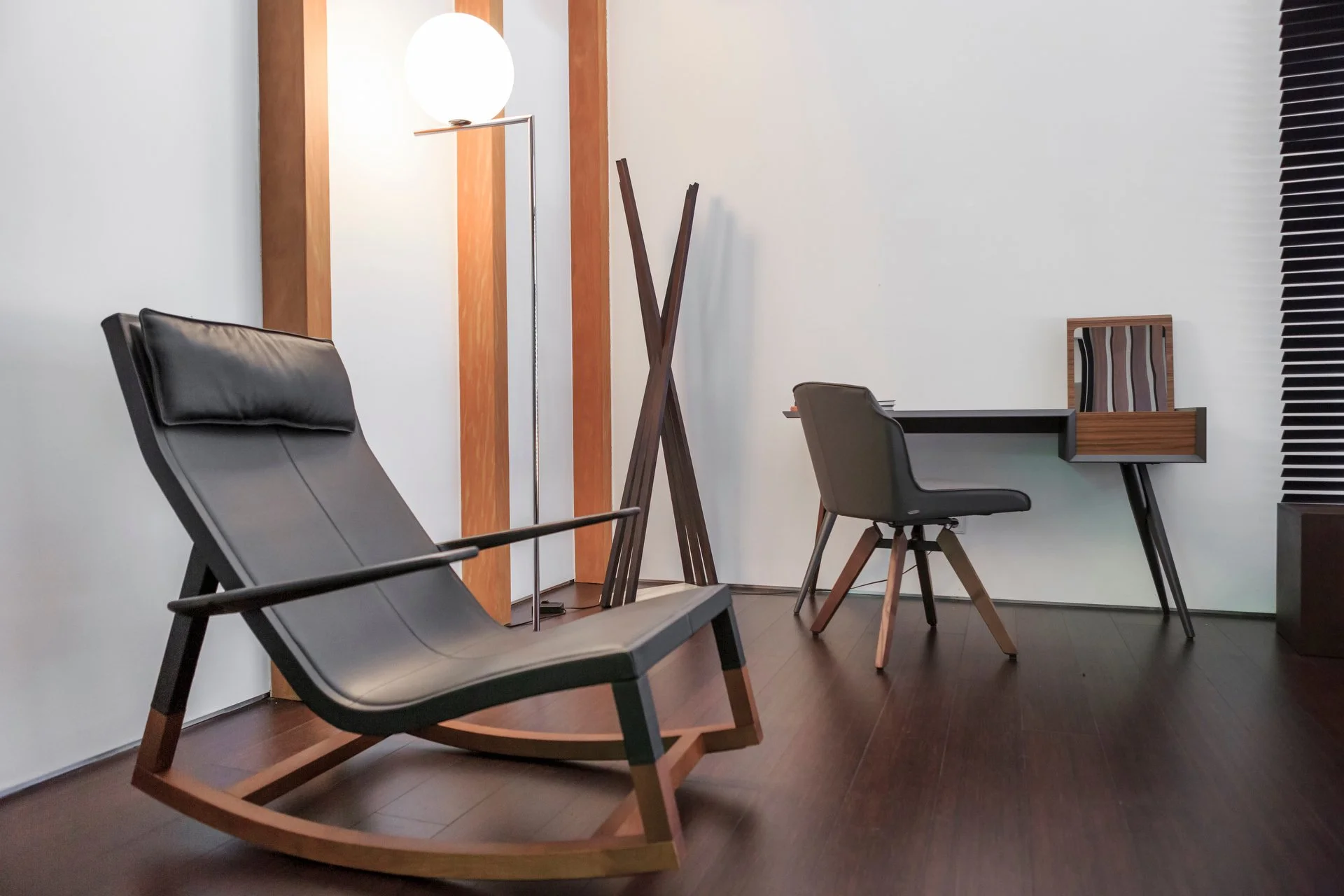 Modern wooden vanity with a grey chair and black leather rocking chair