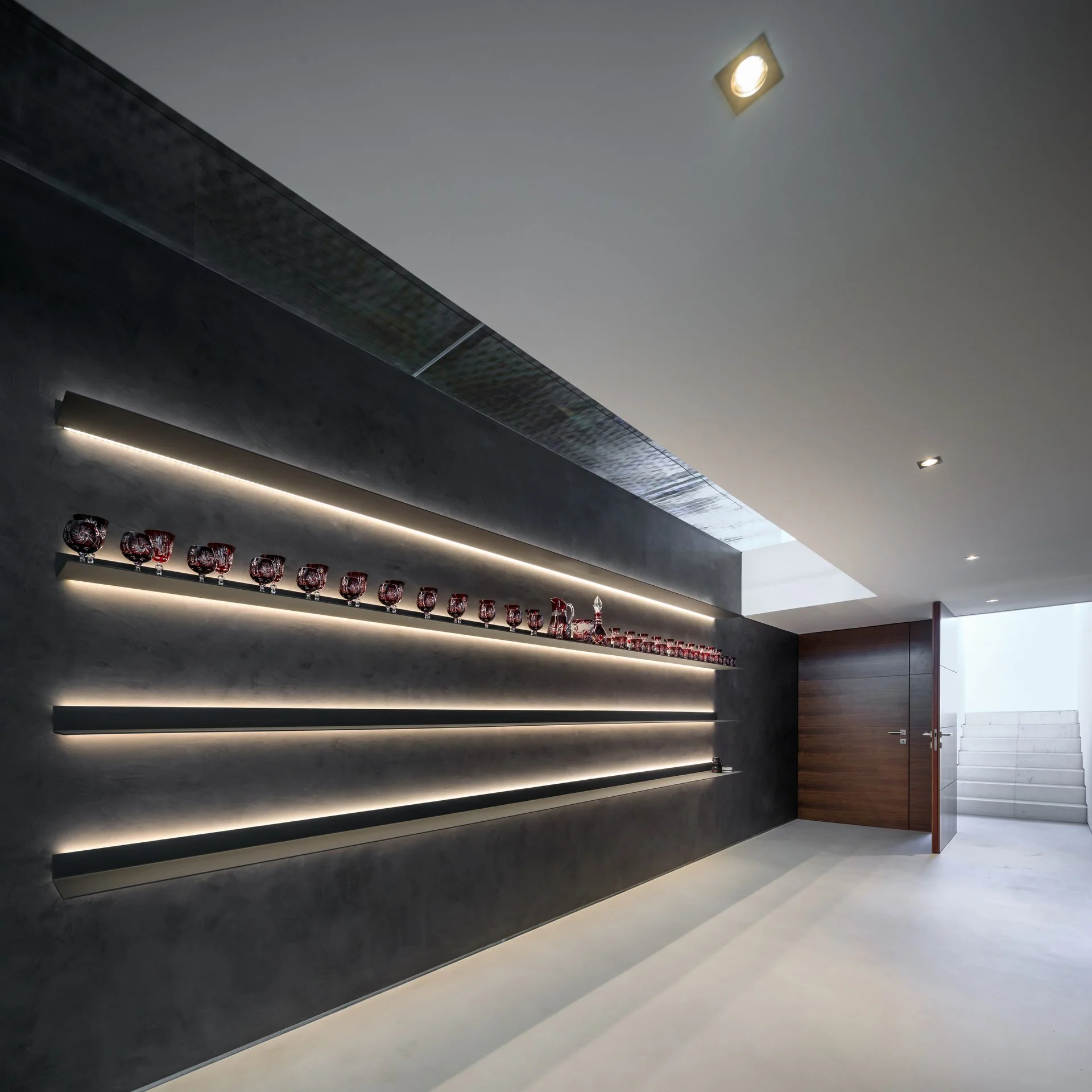 Custom wall design for a hallway in one of A+ Interiors’ projects, in black stone with light strips