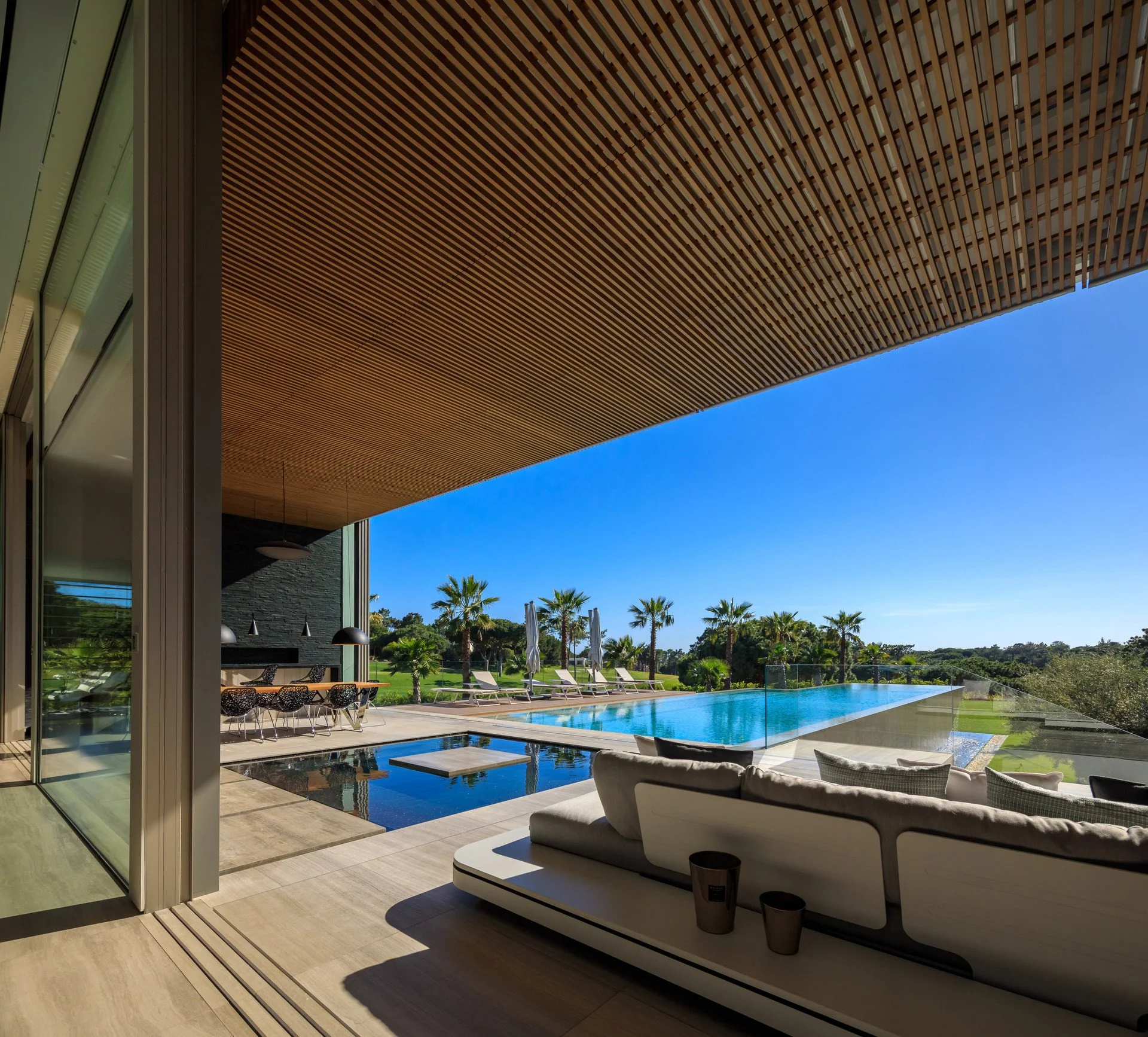 Beautiful outdoor living project by A+ Interiors, featuring an outdoor sofa, dining space and pool area with B&B Italia sunbeds