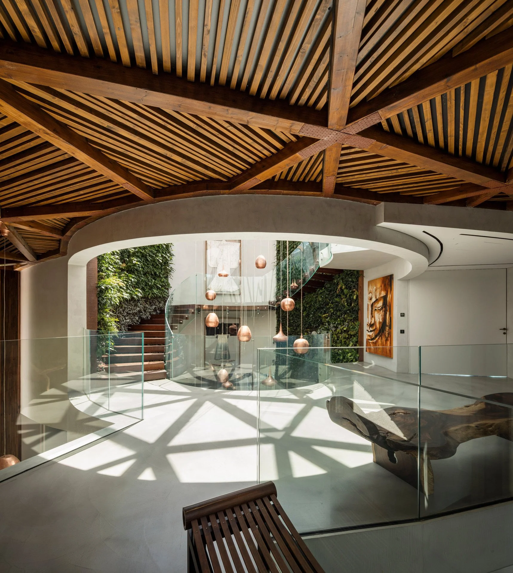Stunning stairwell harmonizing natural and artificial light sources with a statement lighting piece in the middle and a ceiling with an intricate wood design