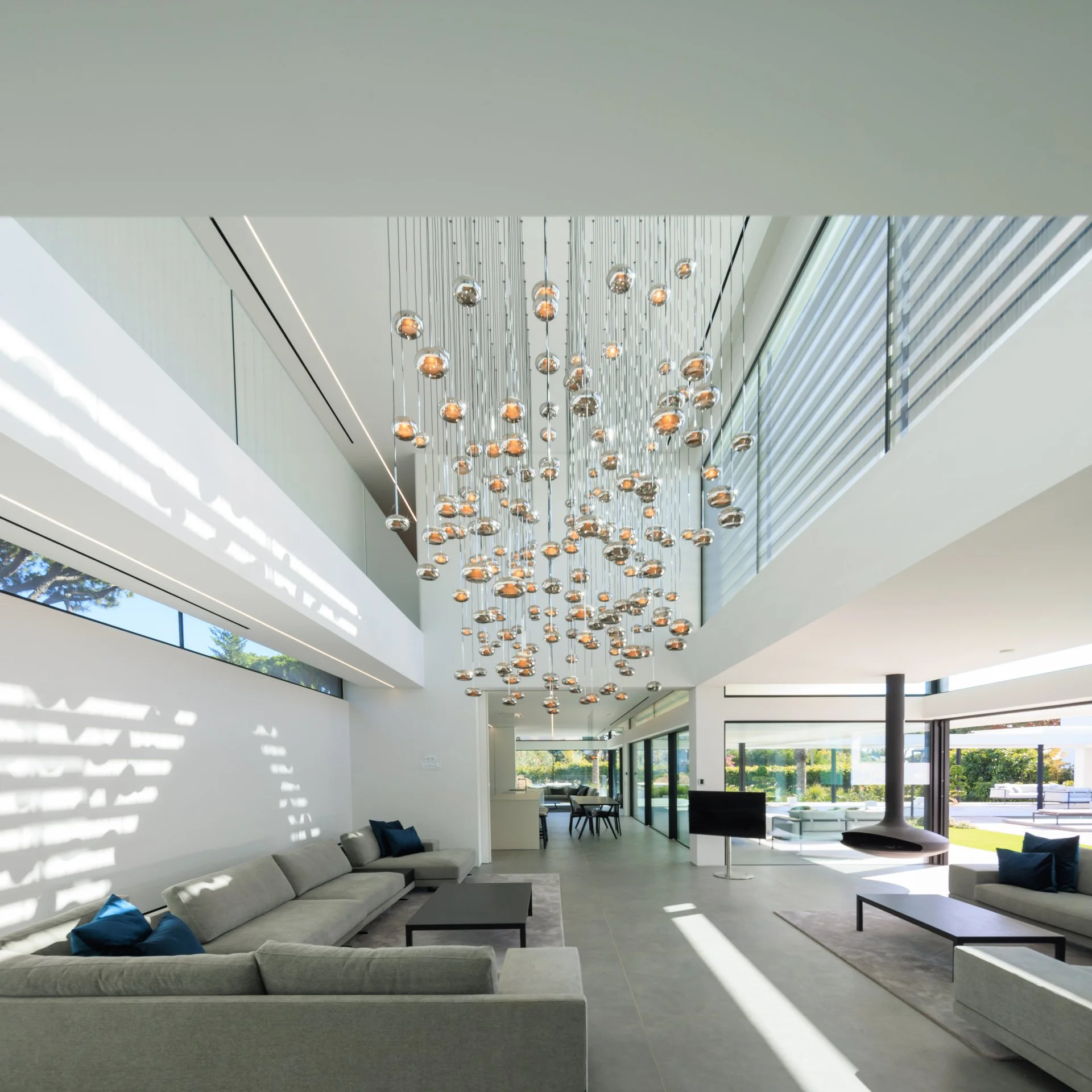 Living room project oozing luxury with double height ceiling and a lighting feature by Beau Design taking center stage