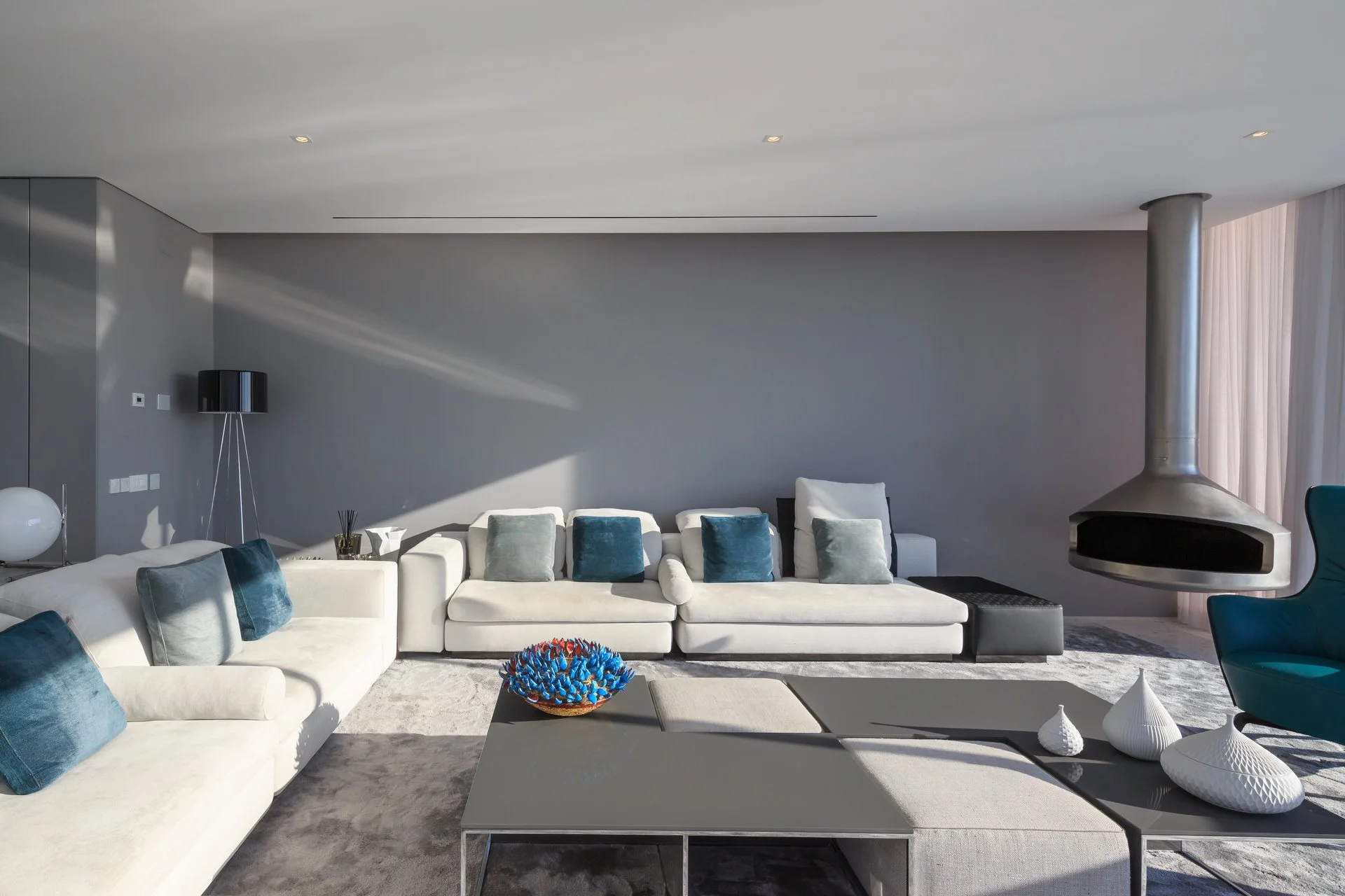 White and blue themed living room with modern furniture and a suspended fireplace