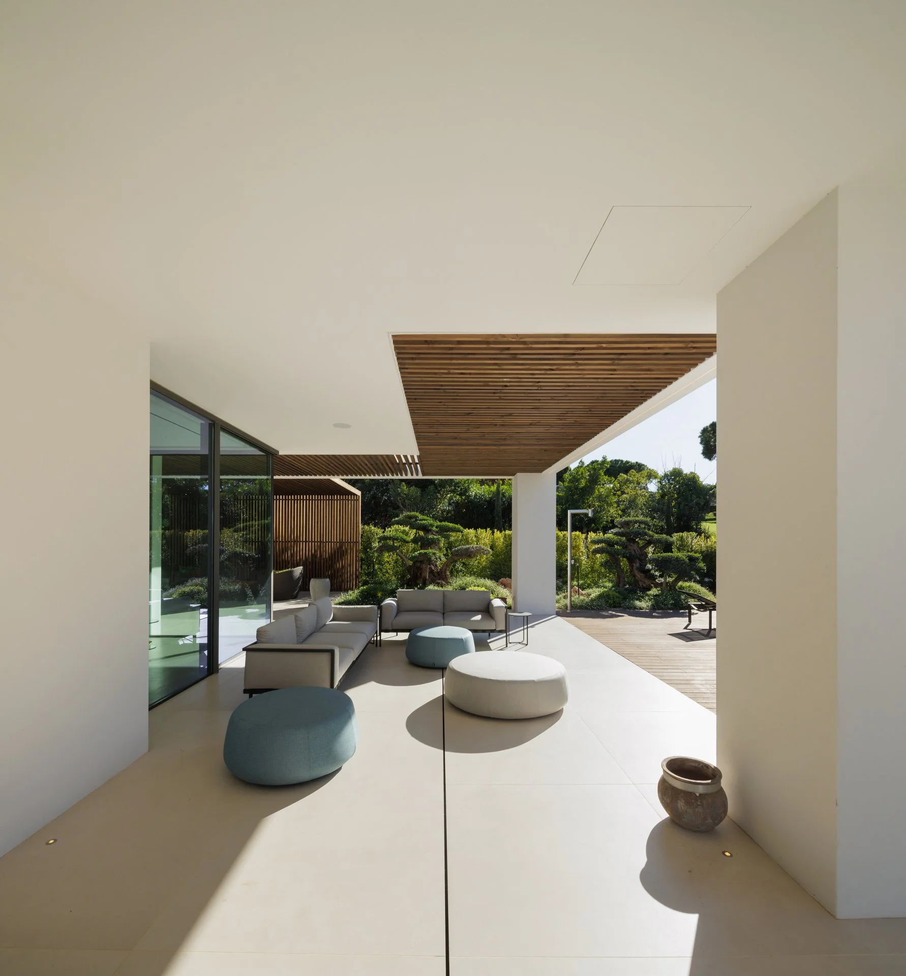 Outdoor living space with pale blue and grey sofa and poufs by our partner Tribù