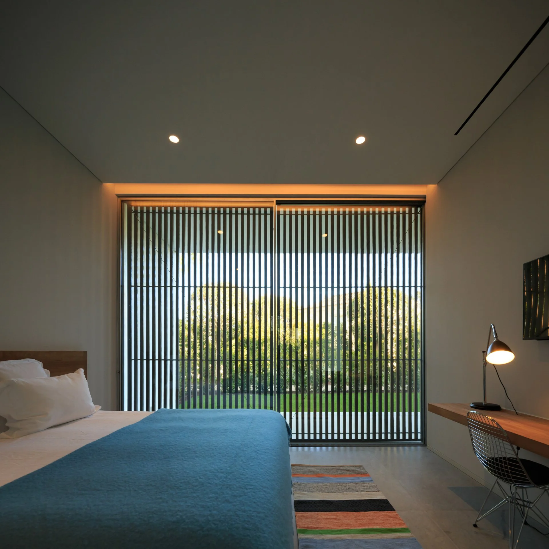 Inviting bedroom in an A+Interiors project with wooden shutters