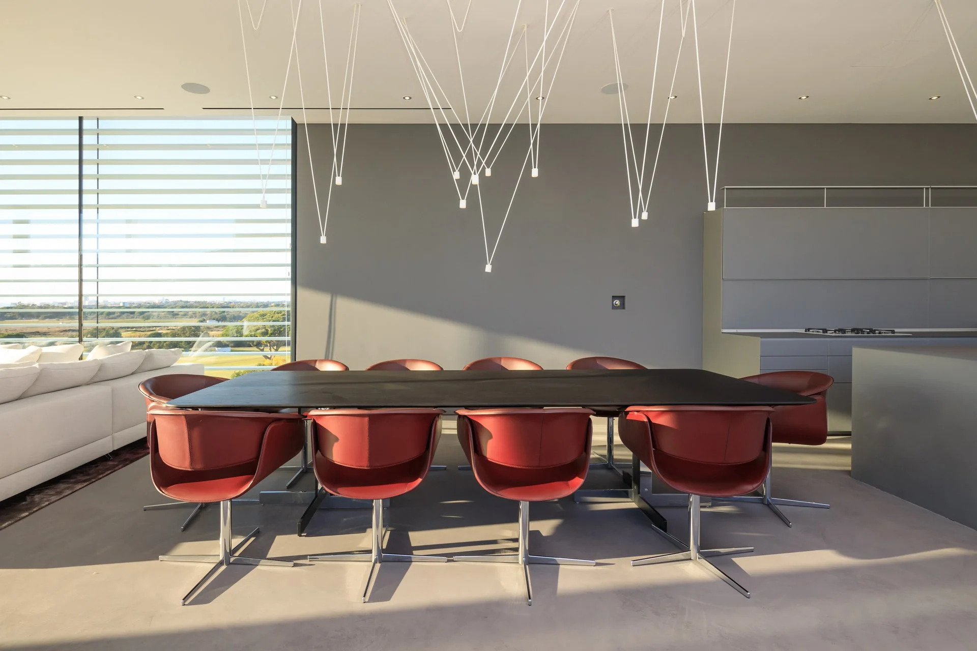 Statement dining space by A+ Interiors with stunning light feature, black dining table and striking red chairs