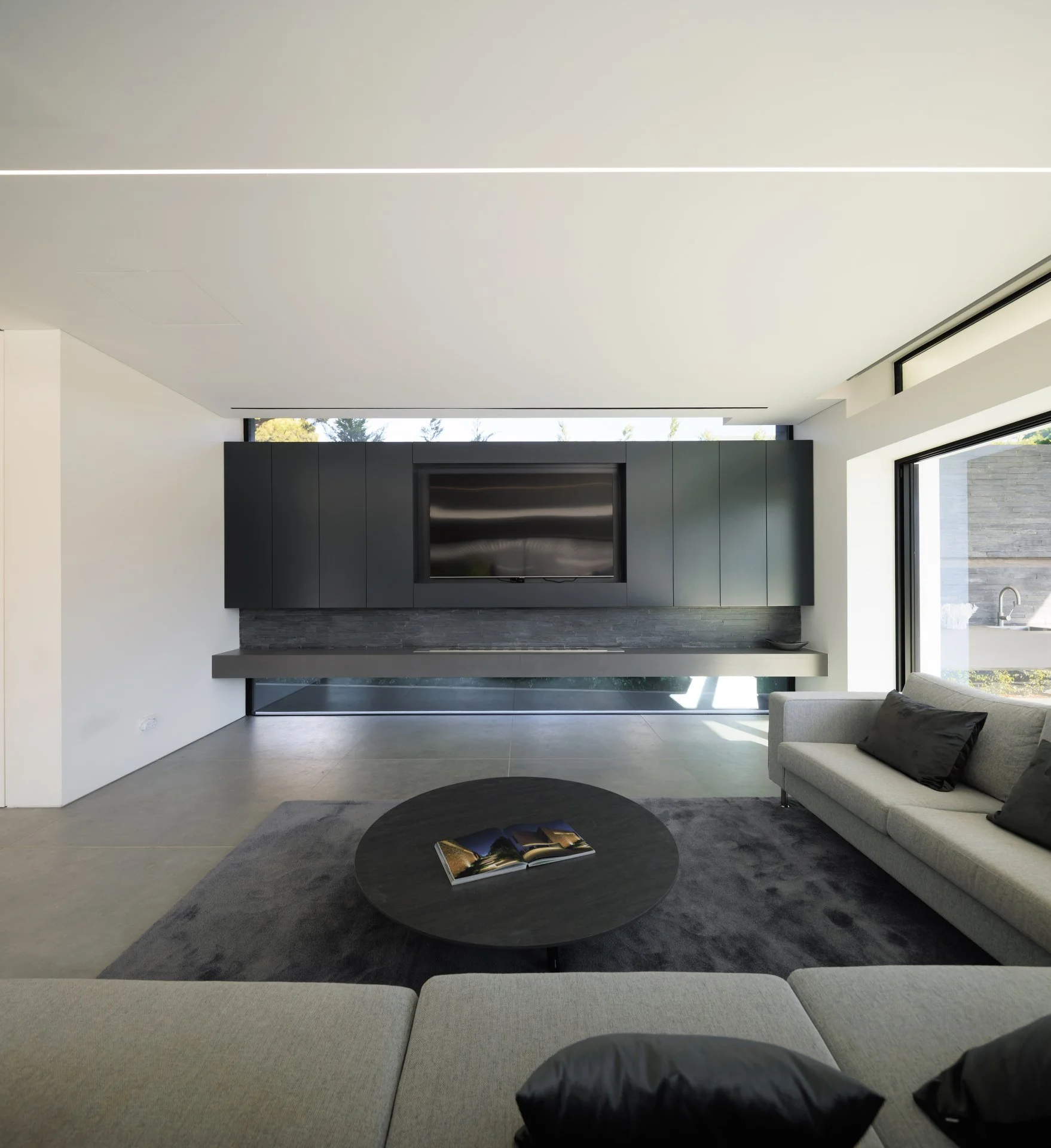 Cozy living room with a grey sofa and a beautiful custom black television unit