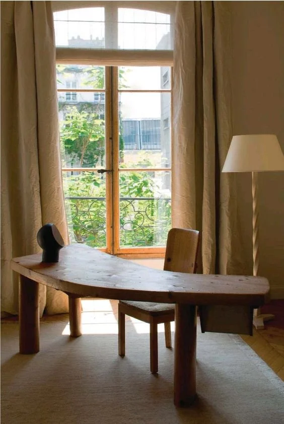 Wooden desk and chair near a window with curtains and floor lamp