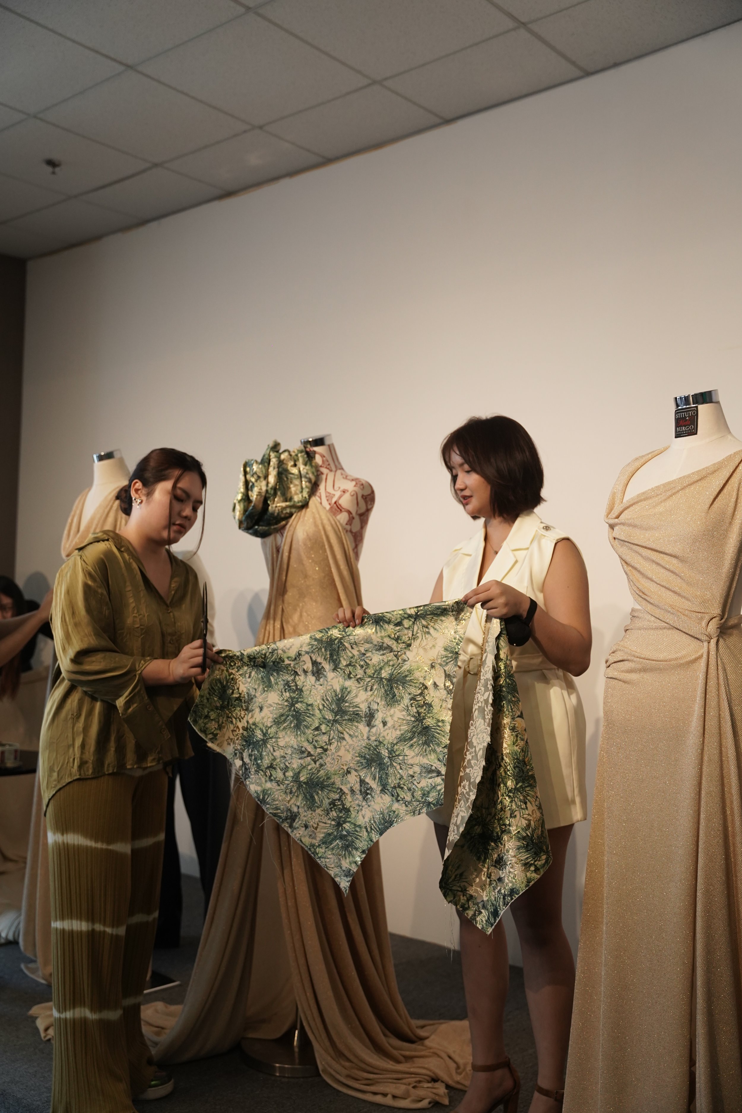 Two women holding a patterned fabric.