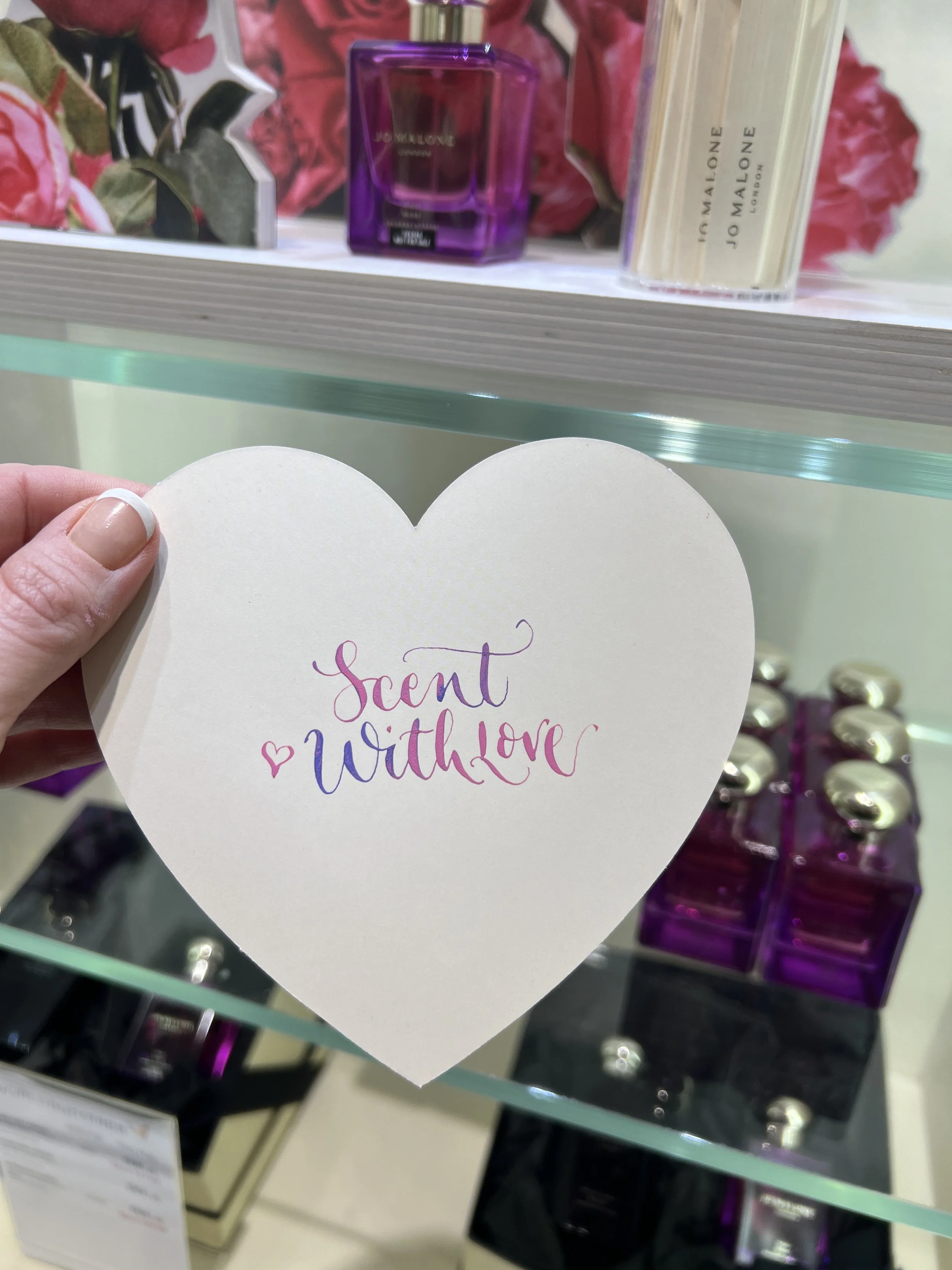 Live calligraphy on heart shaped cards at a Valentine's fragrance brand activation