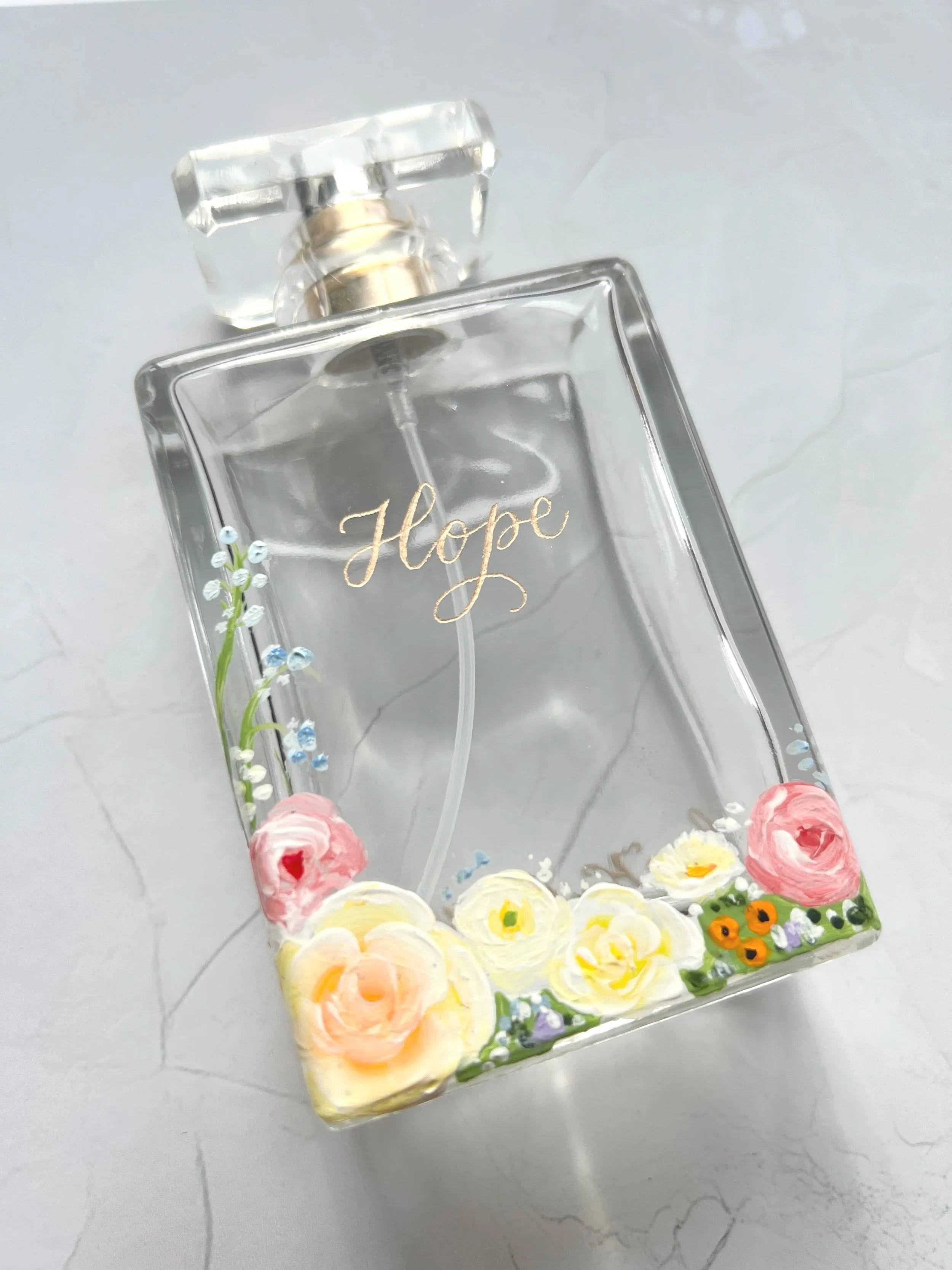Personalised perfume bottle with hand-painted pastel flowers and gold calligraphy name