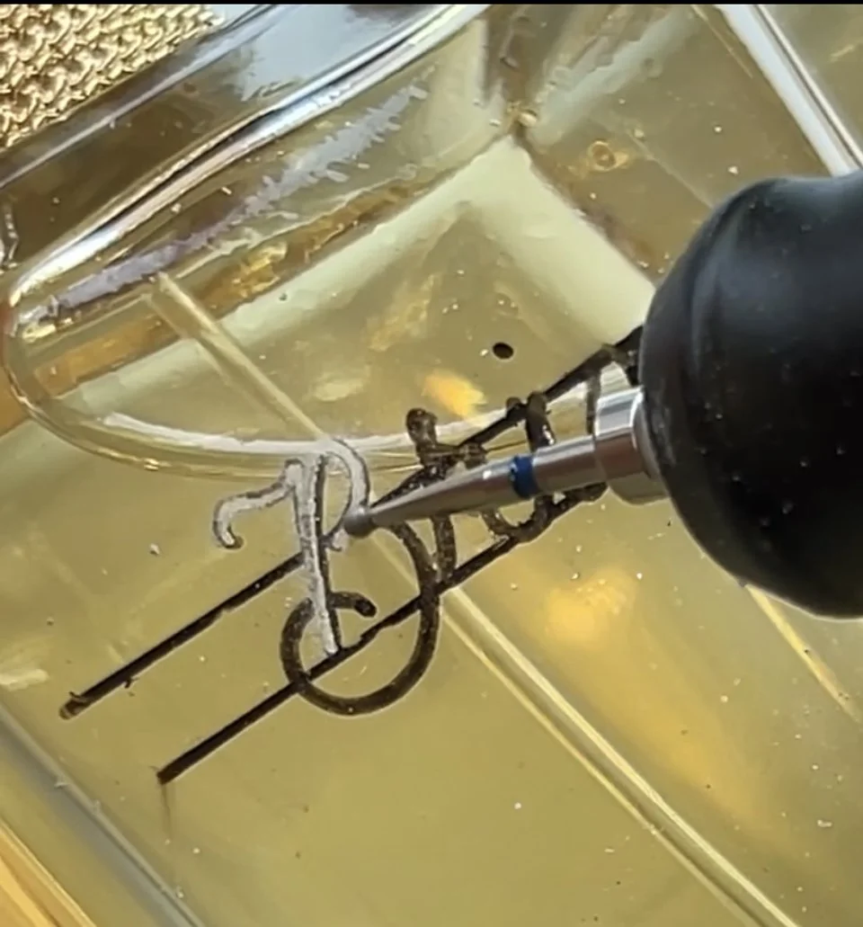 Close-up of hand engraving on glass during a live brand activation