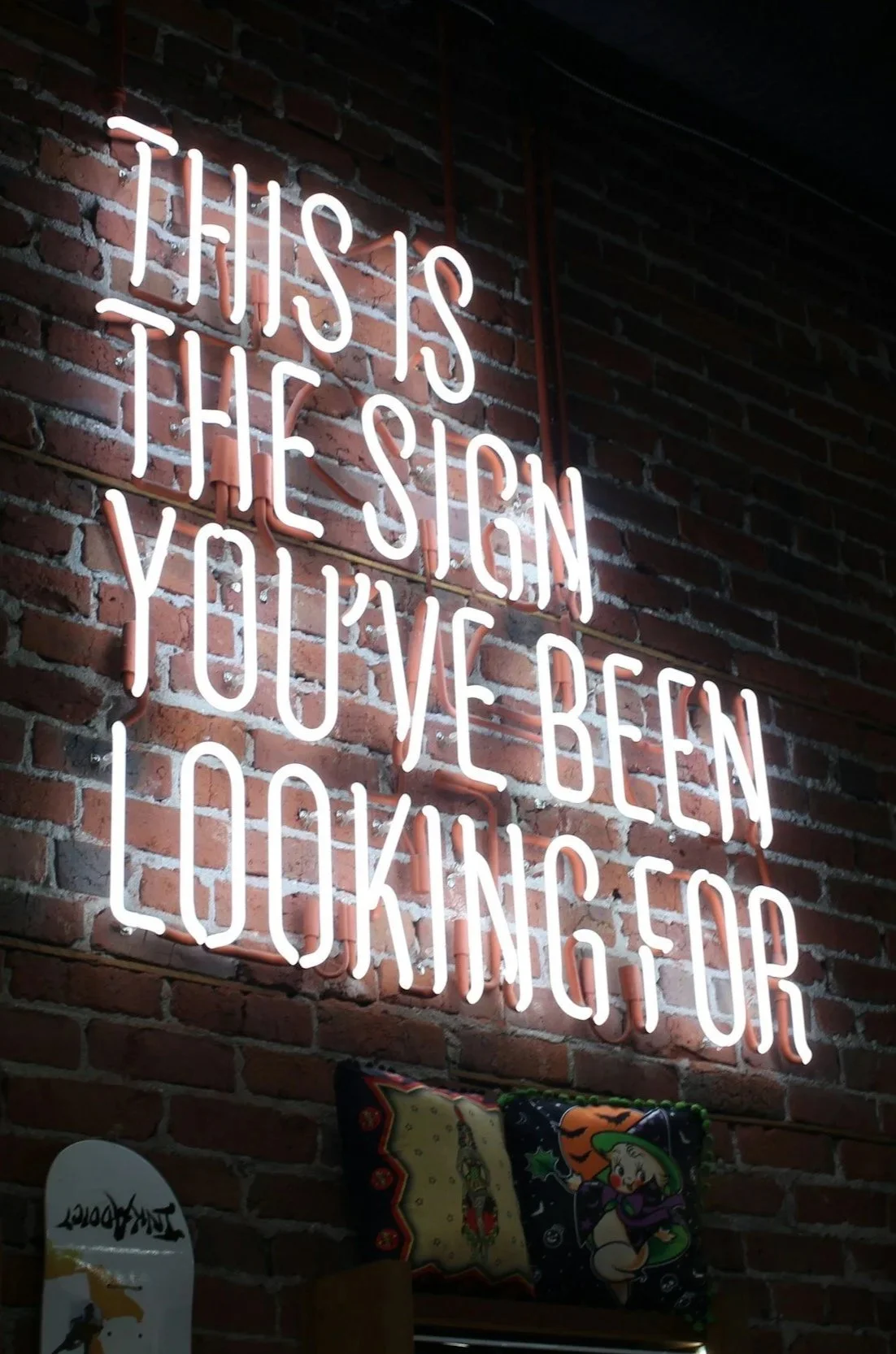 Neon sign on brick wall reading, 'This is the sign you’ve been looking for'.