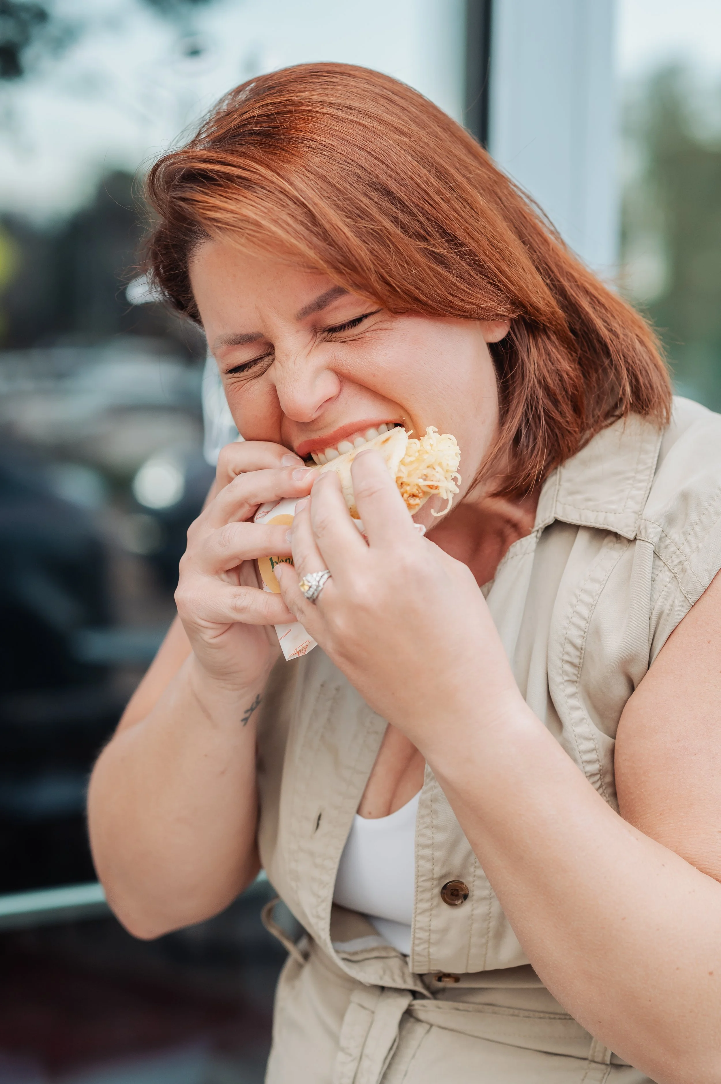 Woman biting into an arepa and visually enjoying the bite very much