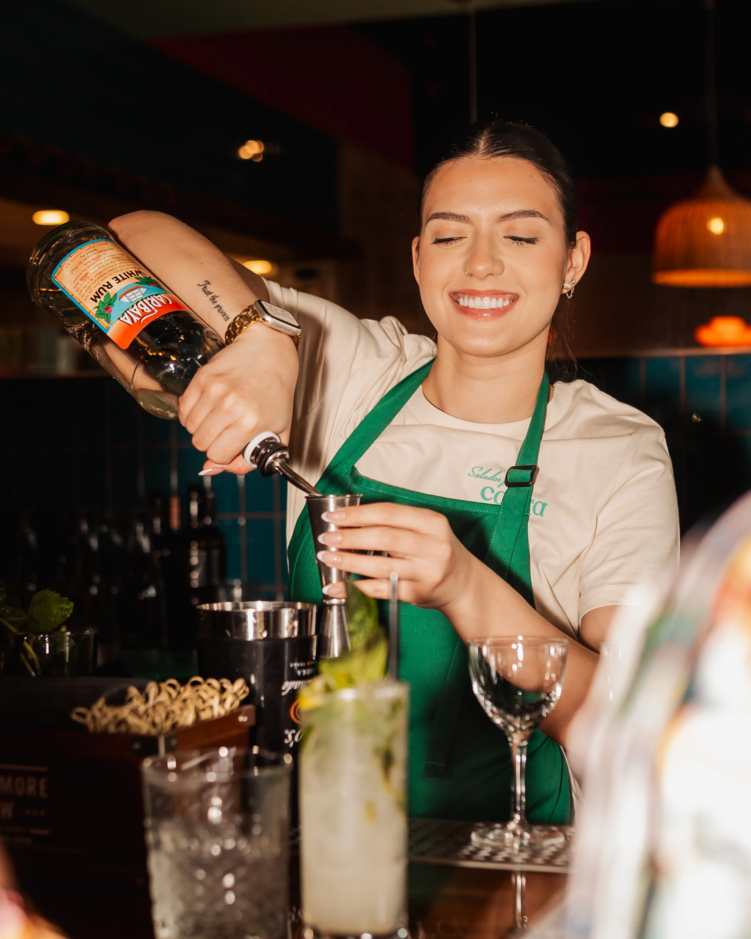 Girl pouring rum into a jigger while making a drink