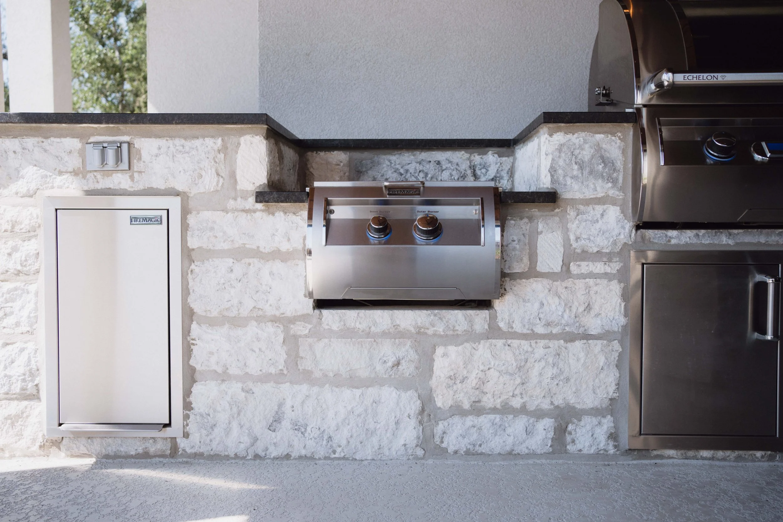 High-end outdoor kitchen by Cozy Fireplace + Patio in San Antonio, Texas featuring stainless steel appliances and stone cabinetry