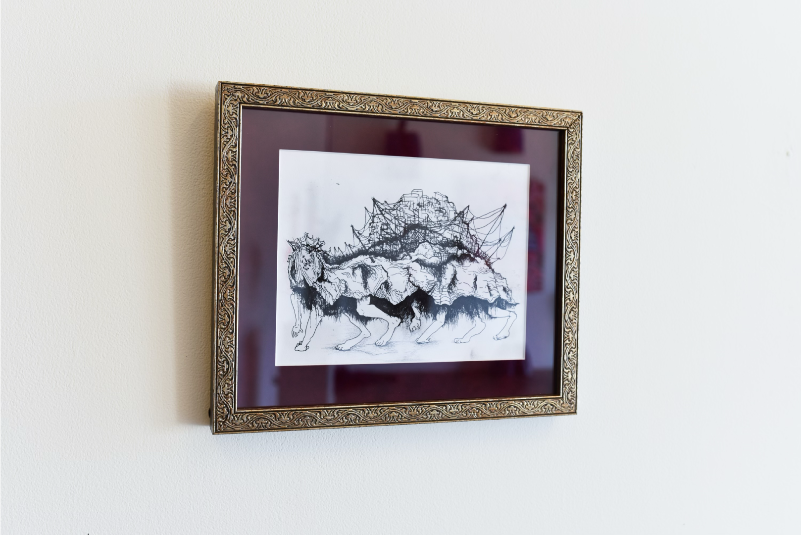 Framed black and white illustration of a fantastical creature with multiple legs and a rocky shell, hanging on a white wall.