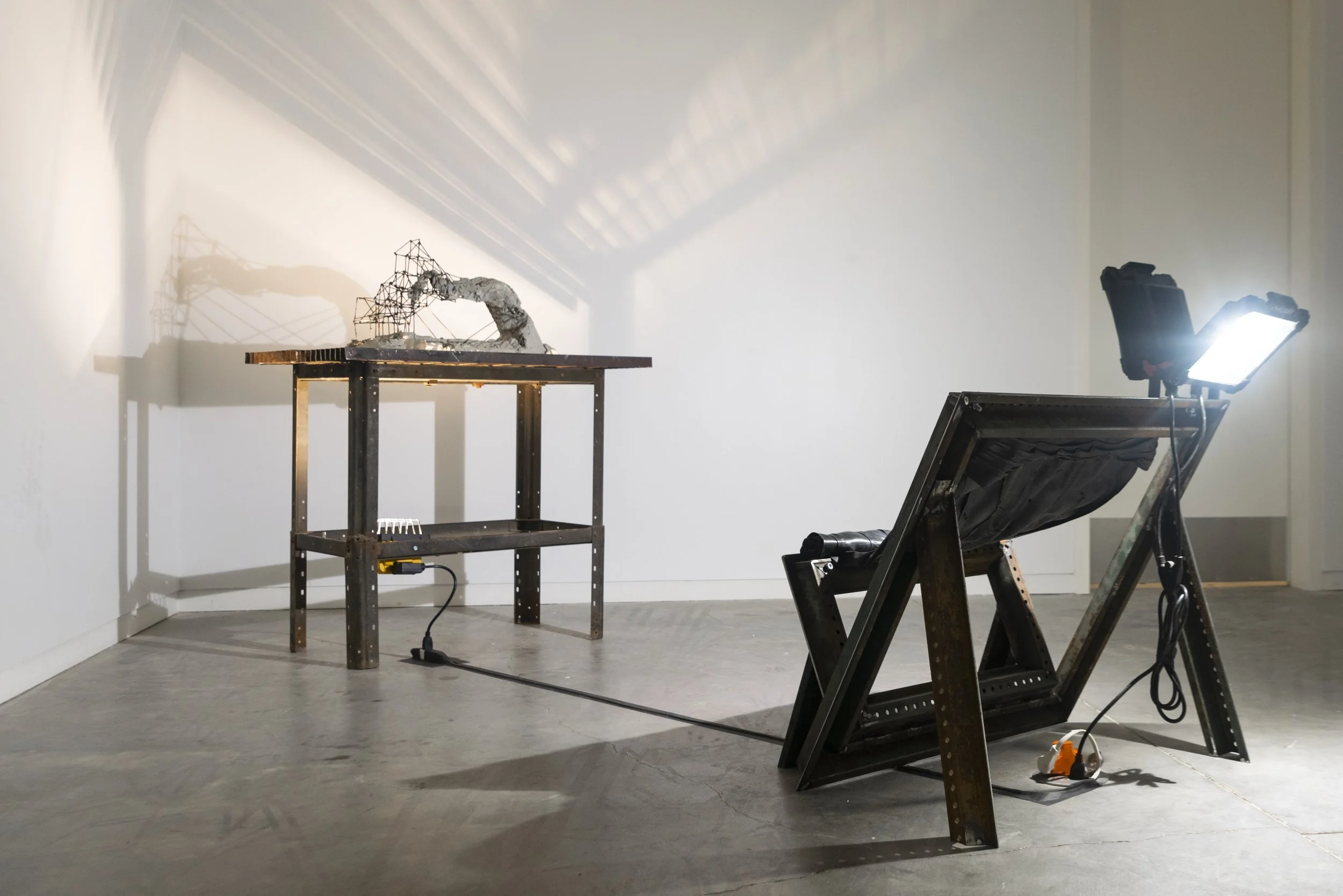 Art installation with metal and light setup casting shadows on a wall.