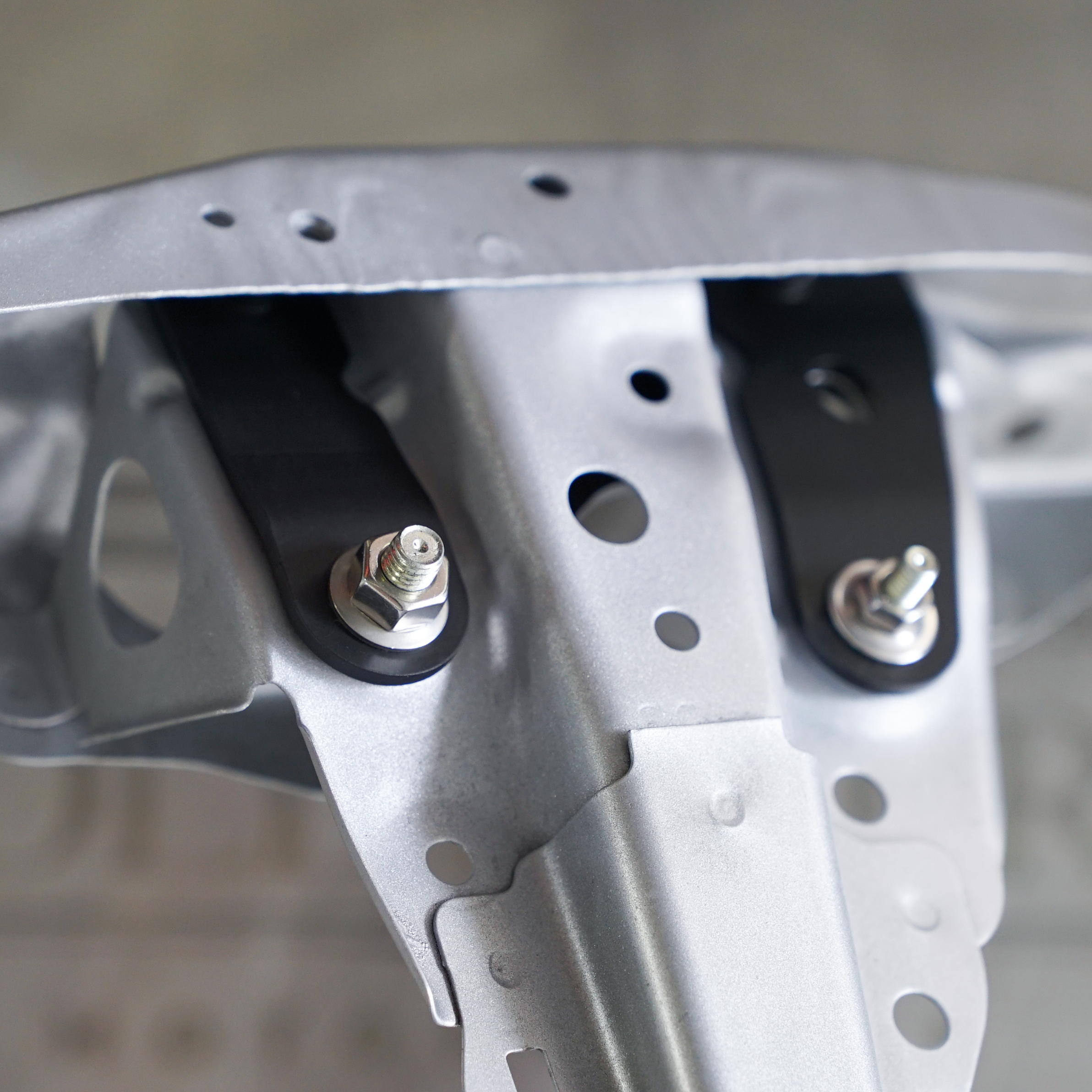 Close-up view of a metallic mechanical part with holes and screws.