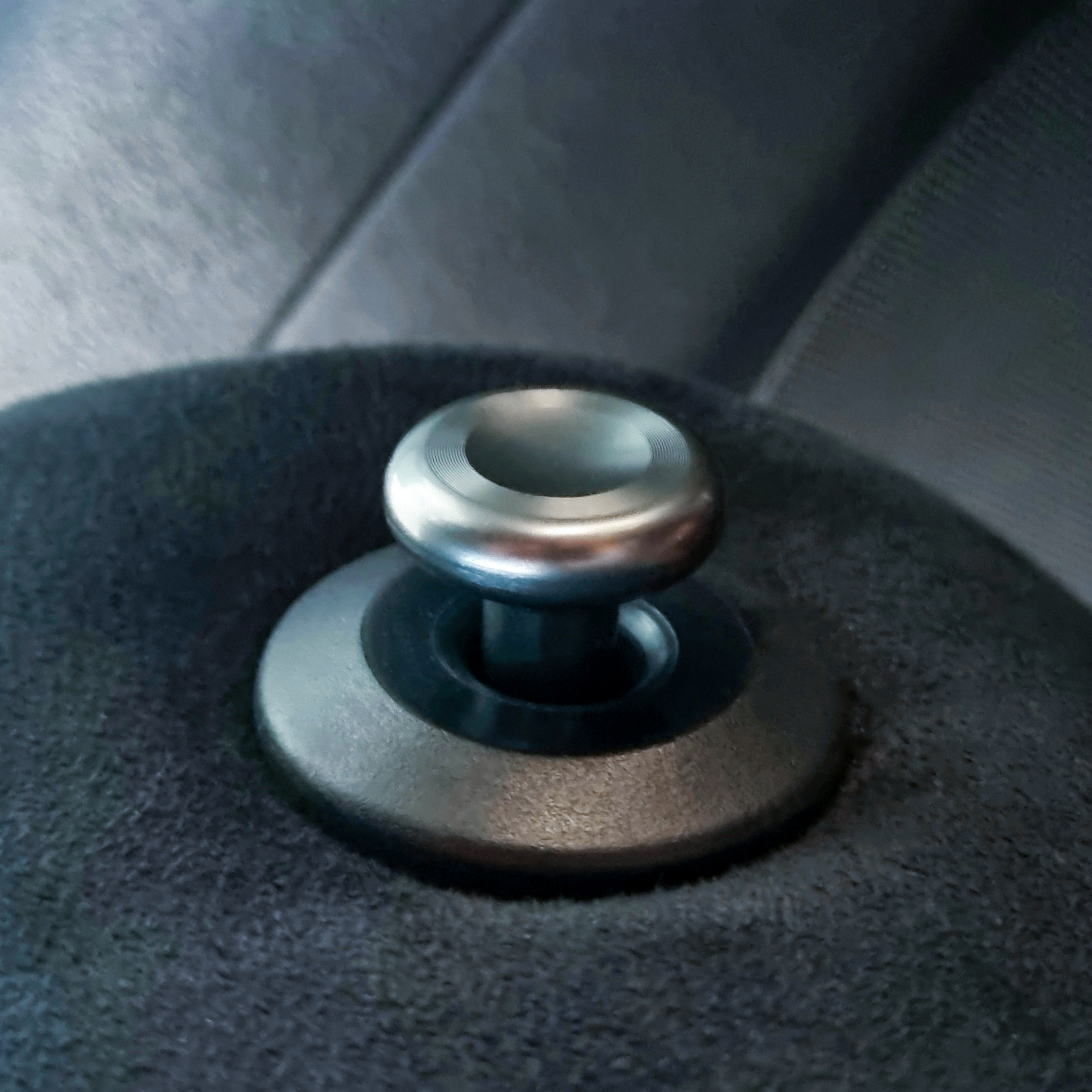 Close-up of a metal bolt in a black textured surface, likely part of a machine or equipment.