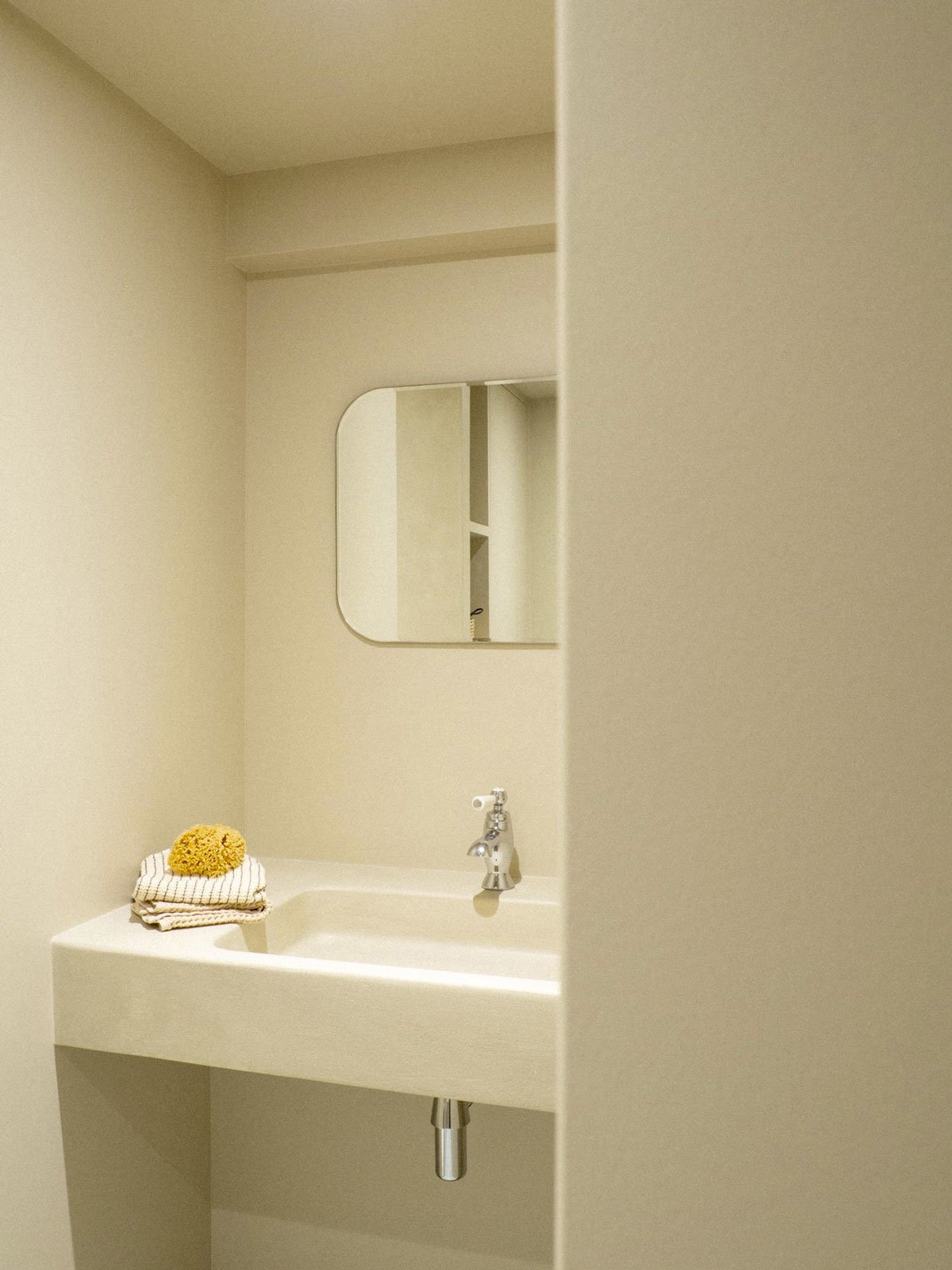 Salle de bain rénovée avec du béton ciré, une vasque maçonnée, de la robinetterie rétro
