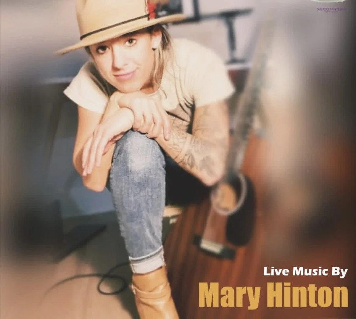 Promotional photo of musician Mary Hint sitting casually with one knee raised, hands clasped around her leg.