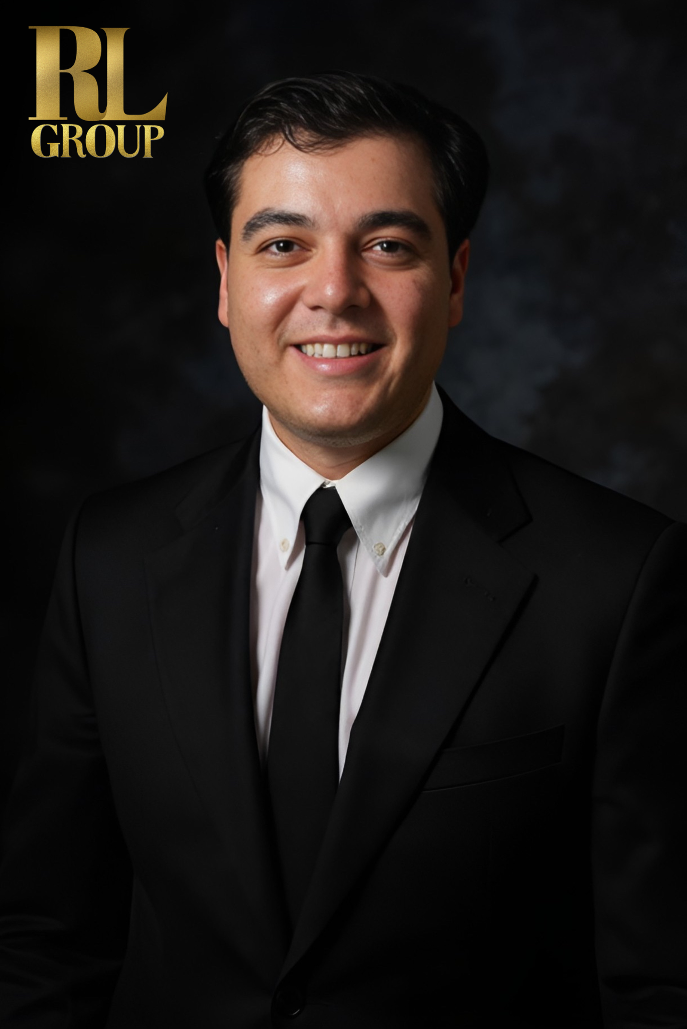 Professional portrait of a smiling man in a black suit, white shirt, and black tie, against a dark background with a gold RL Group logo in the top left corner.