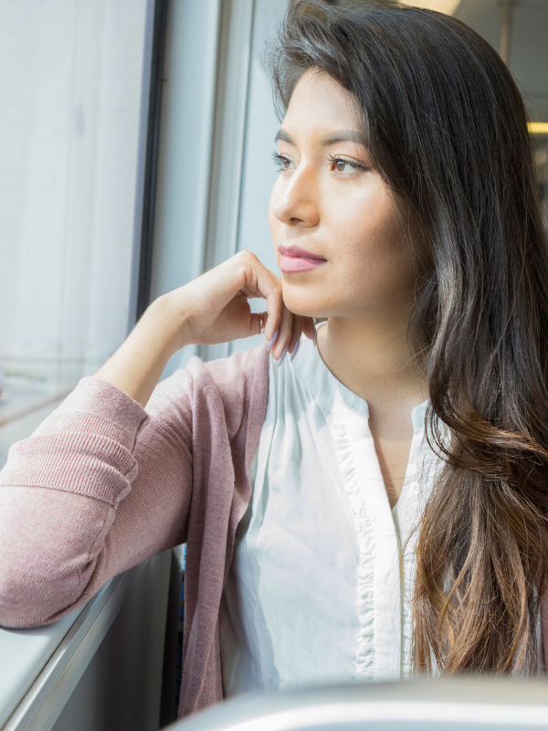 Woman with long hair sitting on a bus gazing out the window.