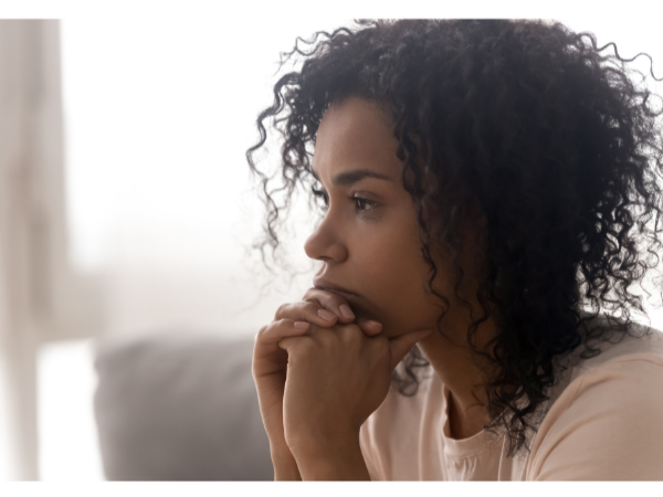 African Amercian mom sitting with hand clasp to her chin.