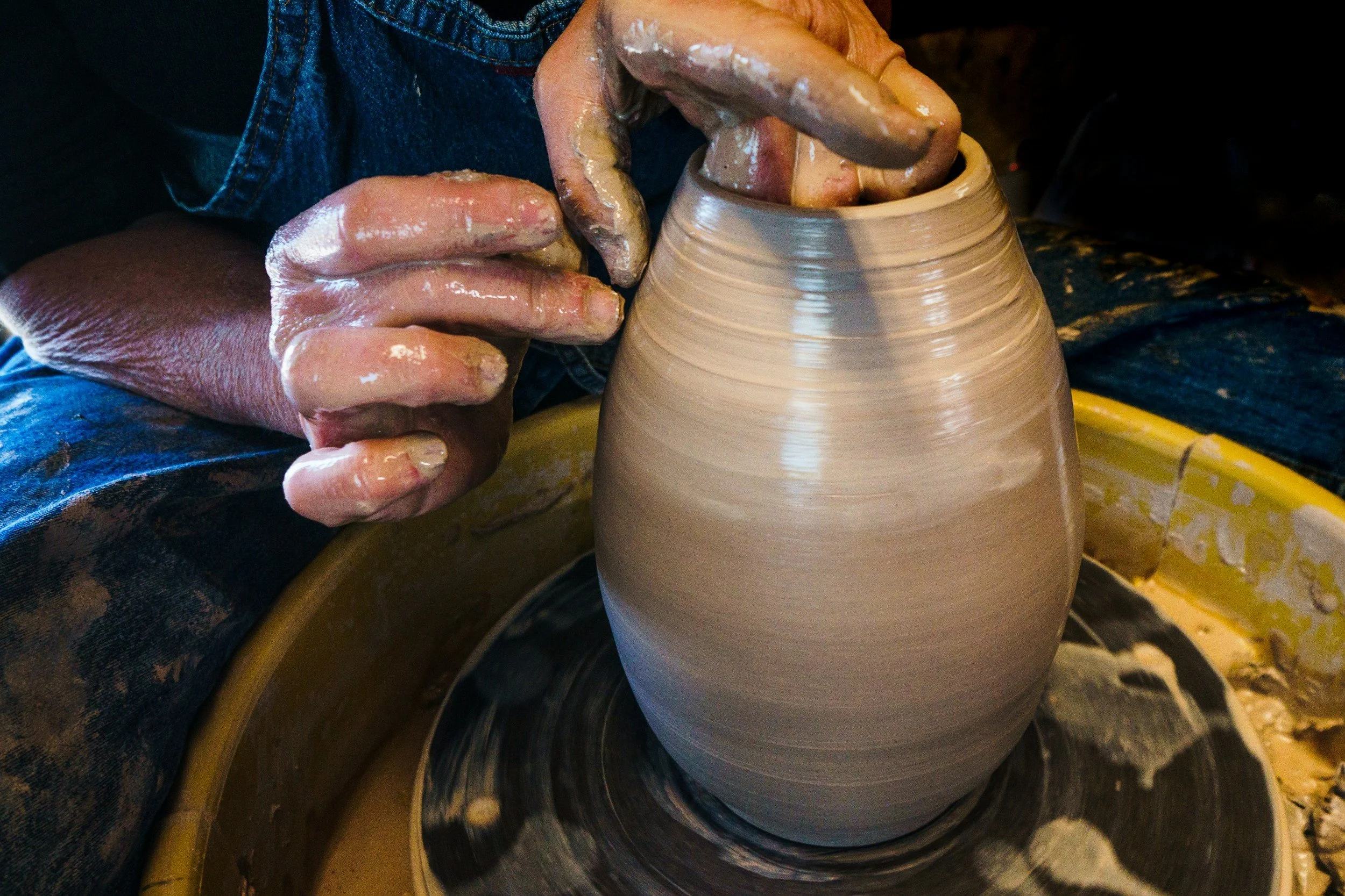 Hands shaping pottery on the potter's wheel.