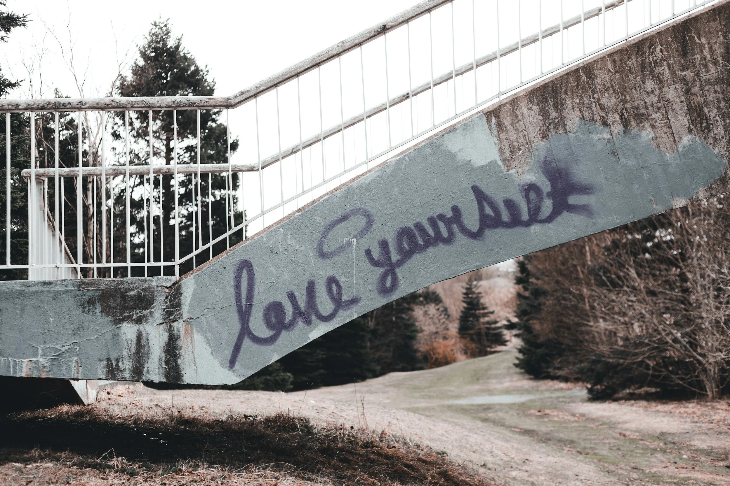 A bridge with the words love yourself written on the side in cursive.