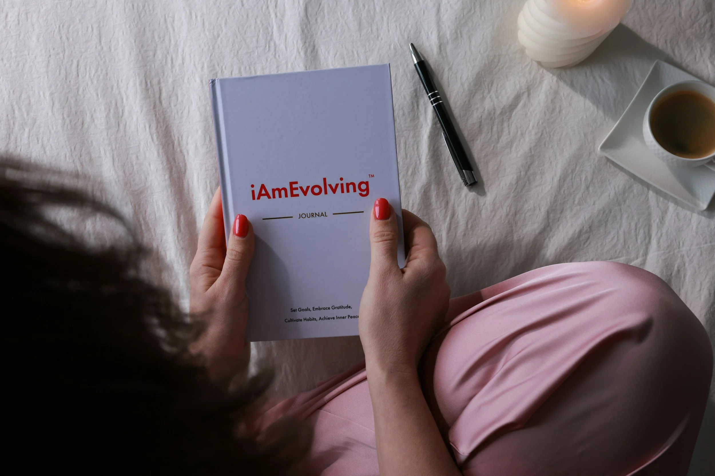 Mother sitting on bed holding a journal that says I am evolving.