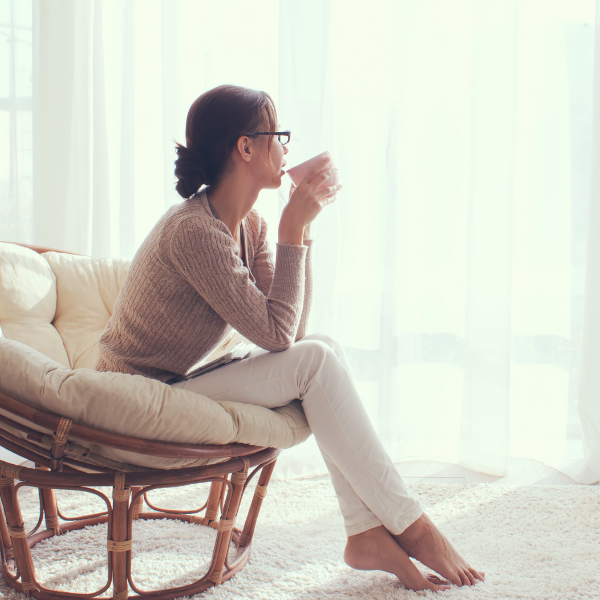 Mom sitting in chair drinking coffee and looking out the window.