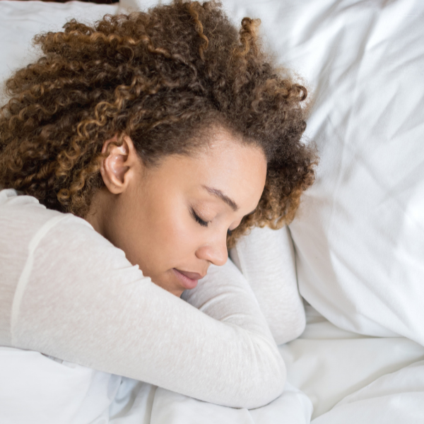 Mom sleeping peacefully in bed with white sheets.