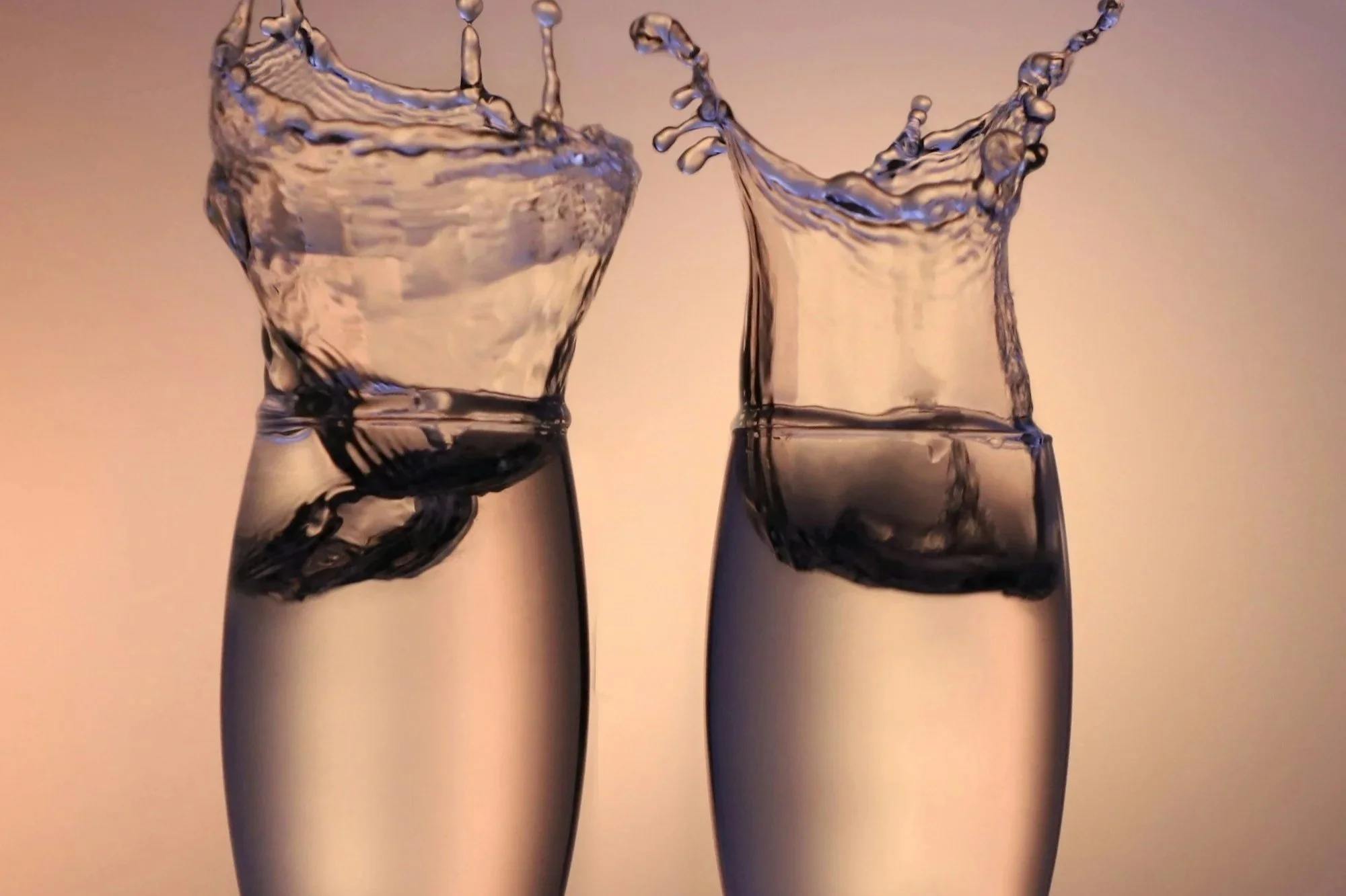 Two clear glasses overfilled with water.