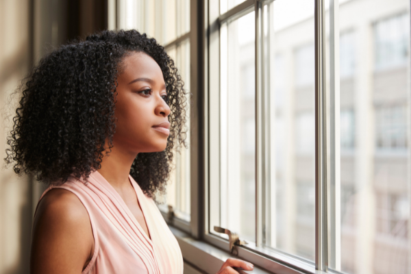 African American mother looking out the window with a soft smile.