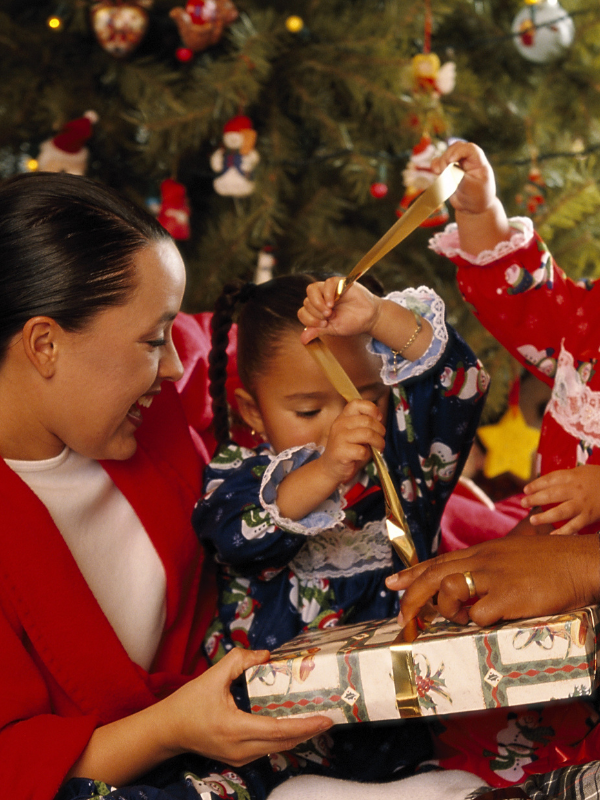 Mom and toddler opening presented in front of the Christmas tree.