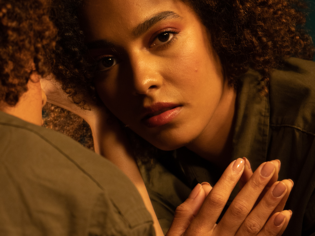 African American mom looking into the mirror exhuasted.