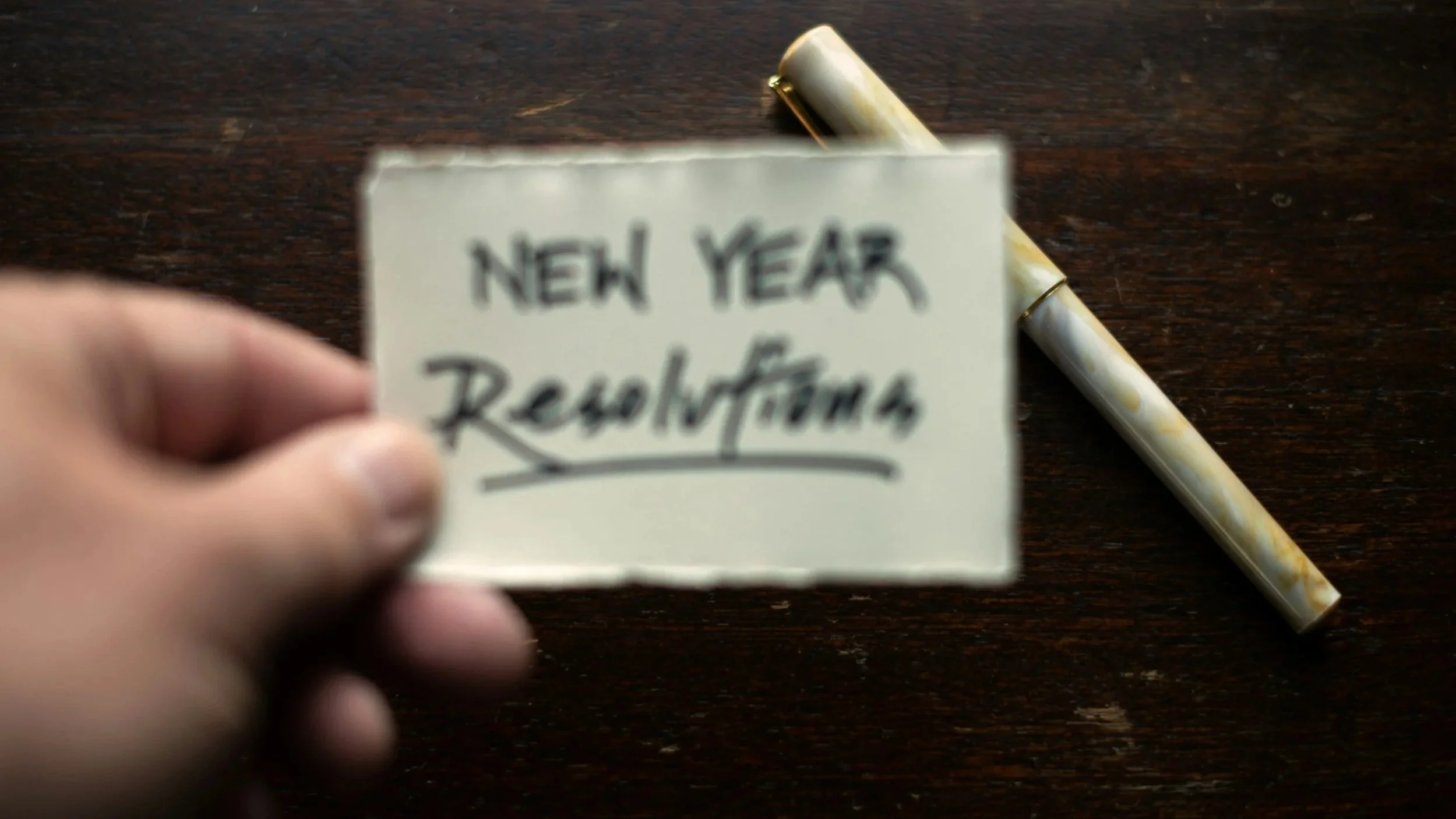 A blurry picture of a hand holding a note that says new year resolutions.