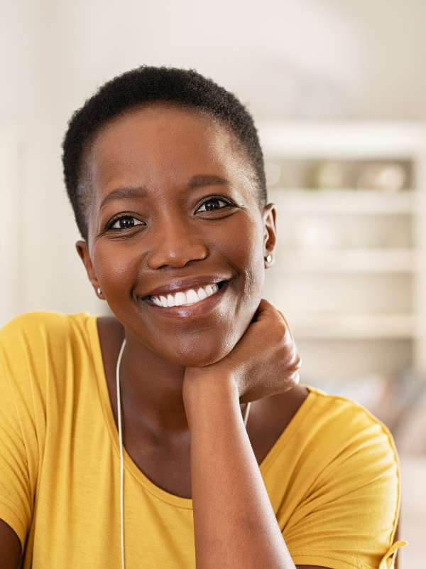 African American mom with a yellow shirt smiling at the camera.