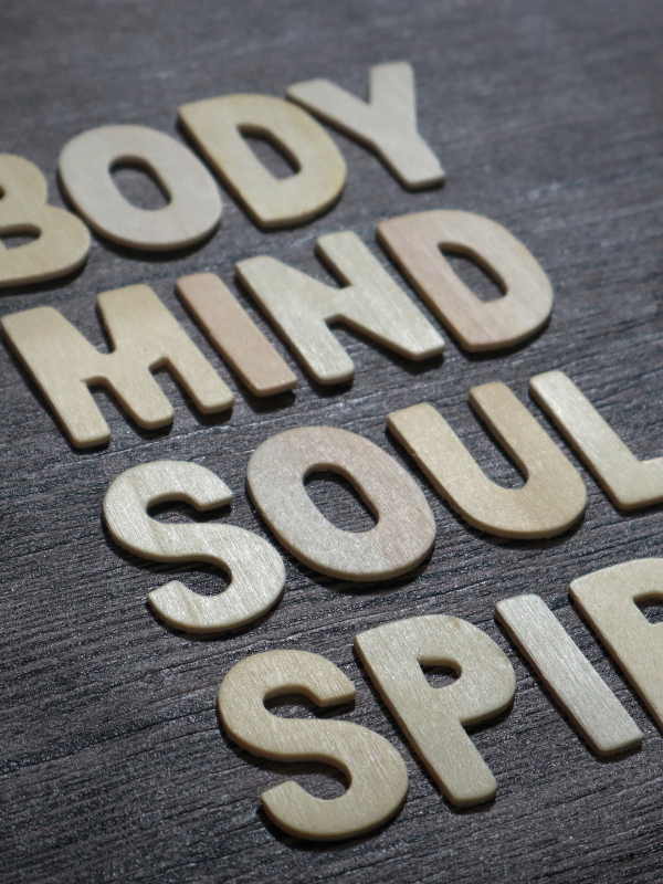 Wood slab with the words body, mind soul spirit.