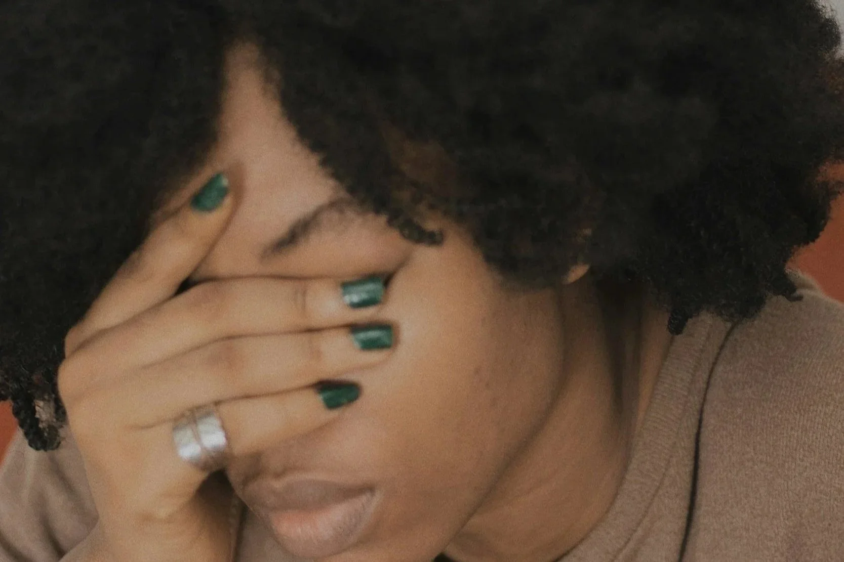 African American mom with face in her hand.