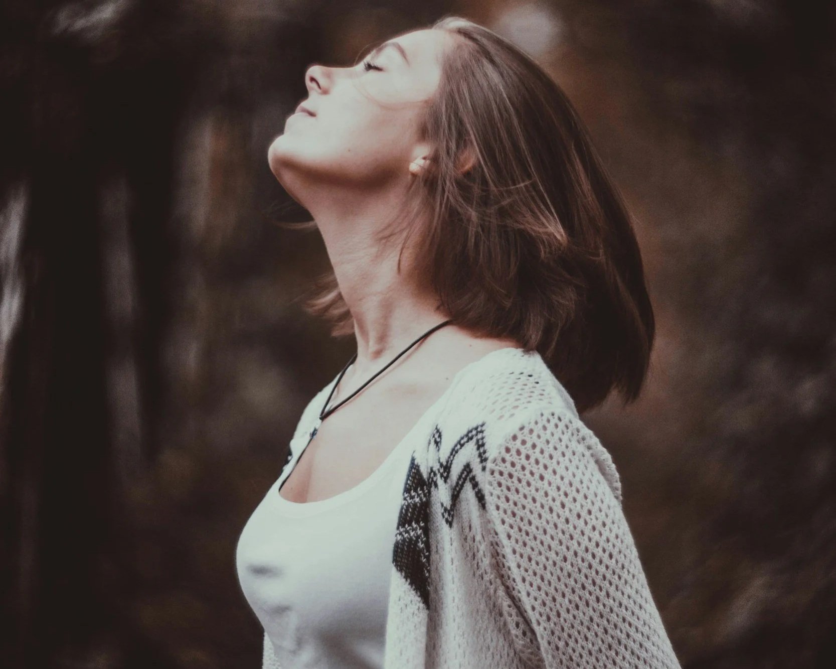 Caucasian woman outside with head lifted and eyes closed.